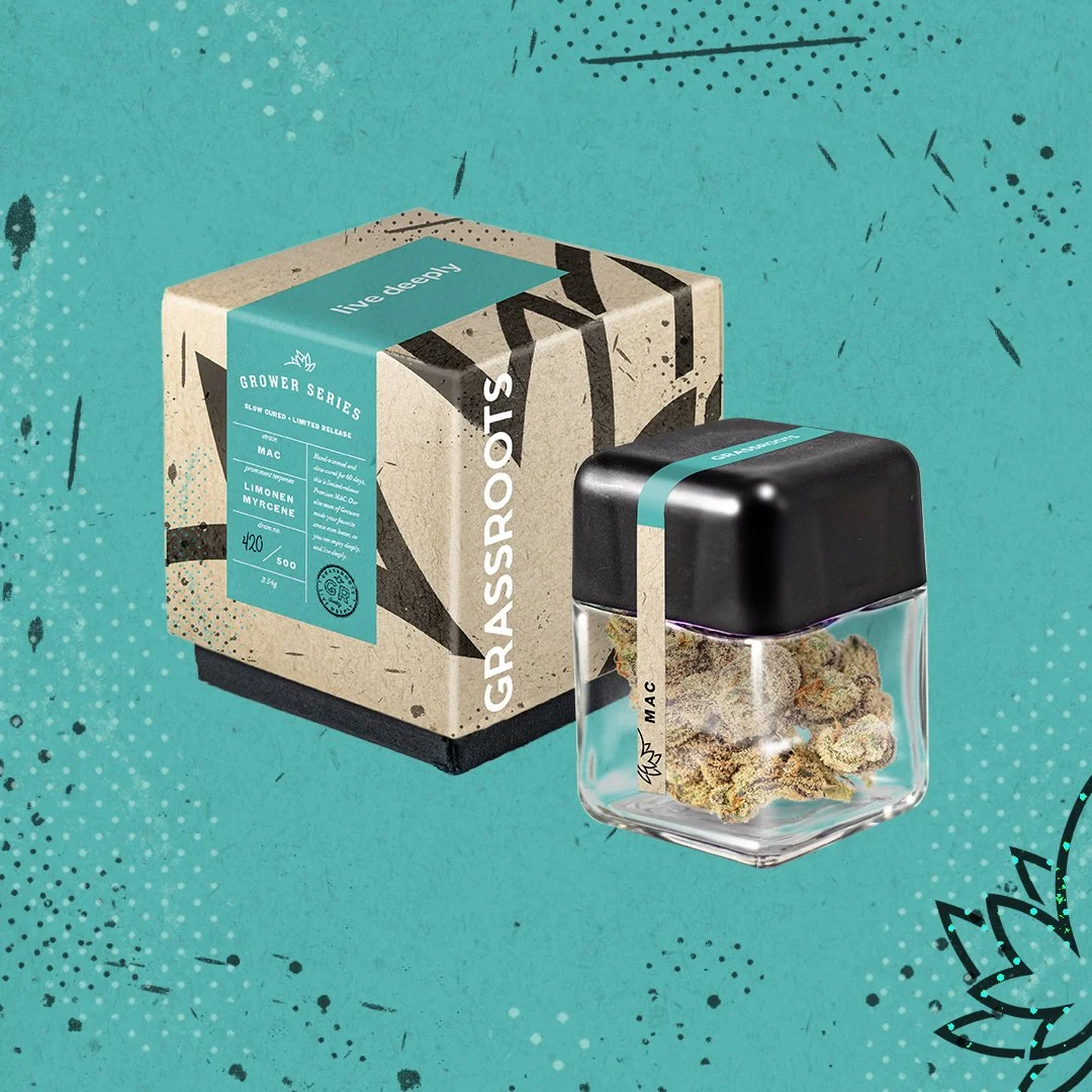 A box labeled 'GRAASS:ROOTS' and a glass jar with a black lid containing cannabis buds, set against a teal background with black and white decorative splatters and patterns.