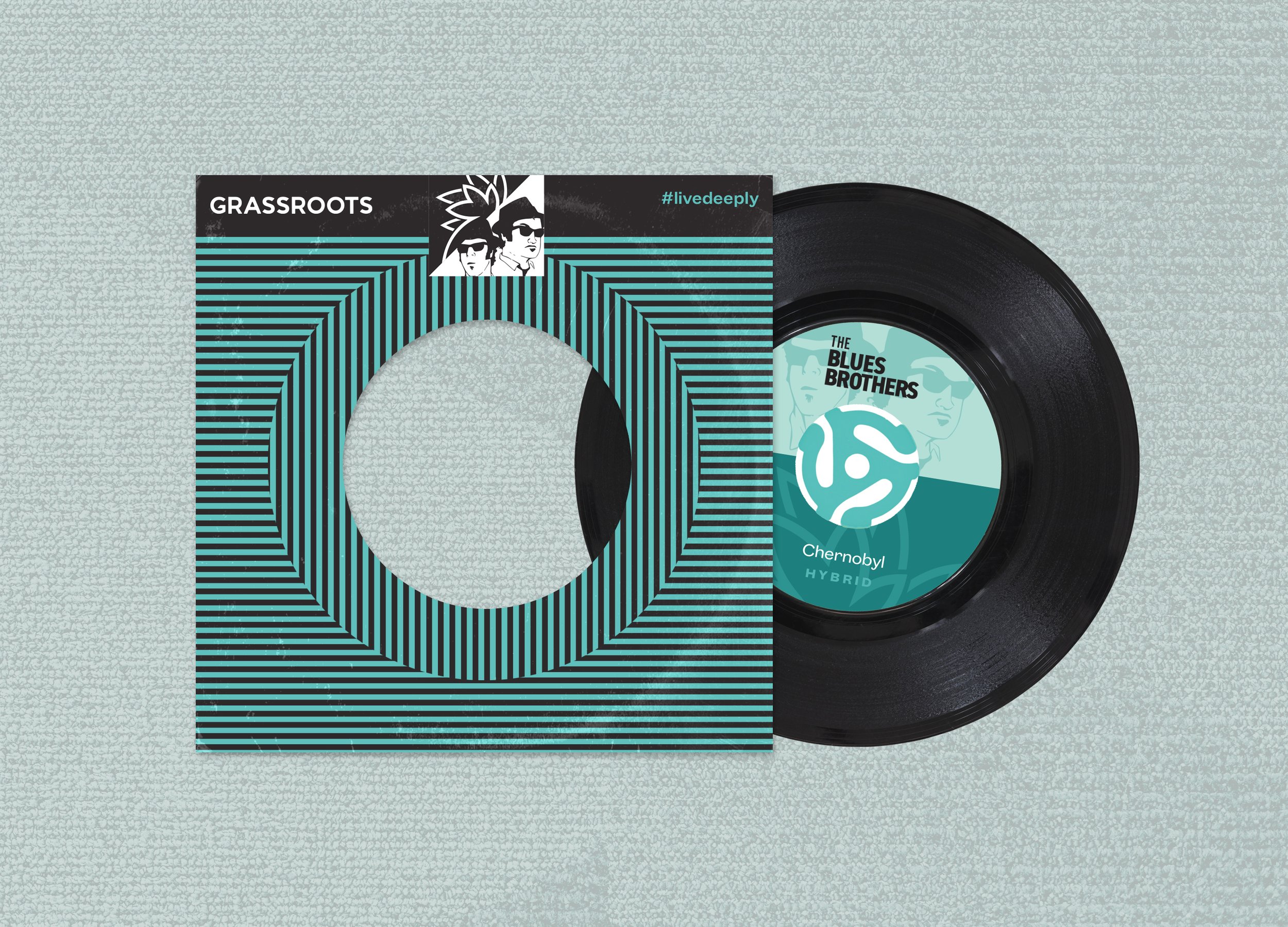 A vinyl record partially inside a cover with a black and teal geometric design, placed on a textured light gray surface.
