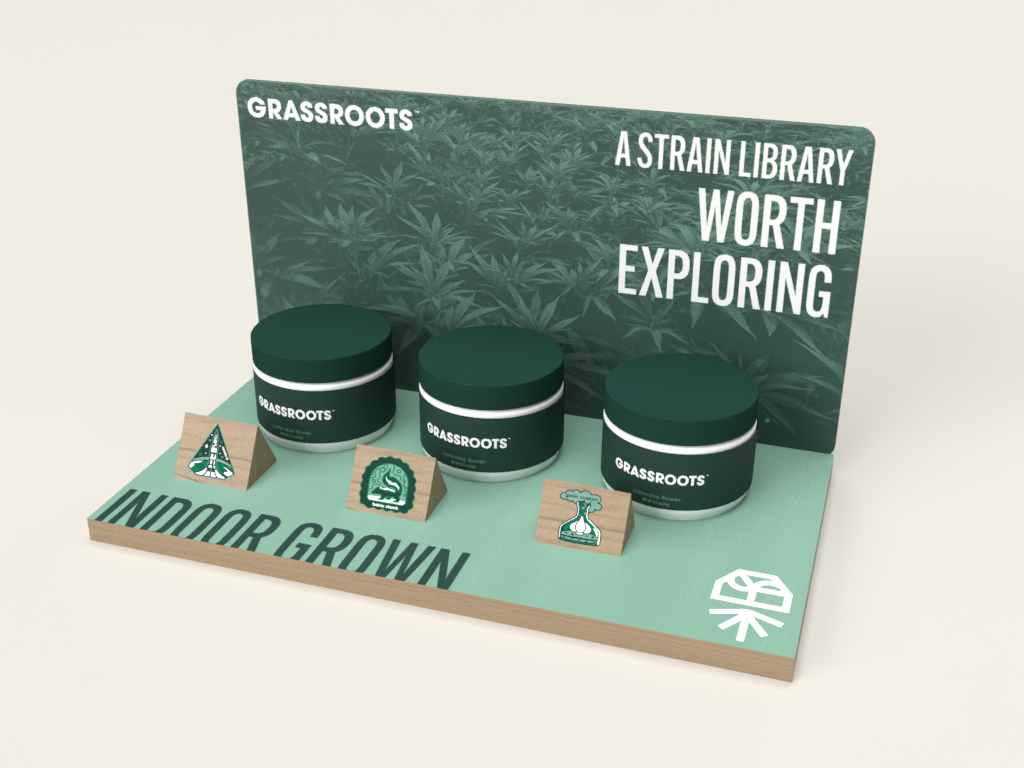 Display stand showcasing three containers and two triangular signs with badges related to indoors and outdoor cannabis cultivation, labeled 'Indoor Grown' with a leaf logo, and featuring a backdrop with a cannabis plant pattern and text about grassroots strain library.