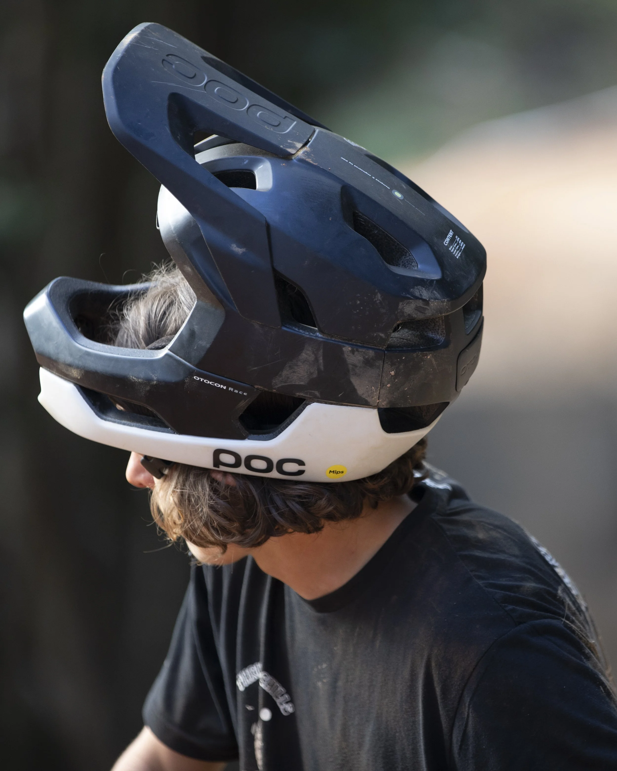 Person wearing a black shirt with a bicycle helmet on their head, outdoors during daytime.