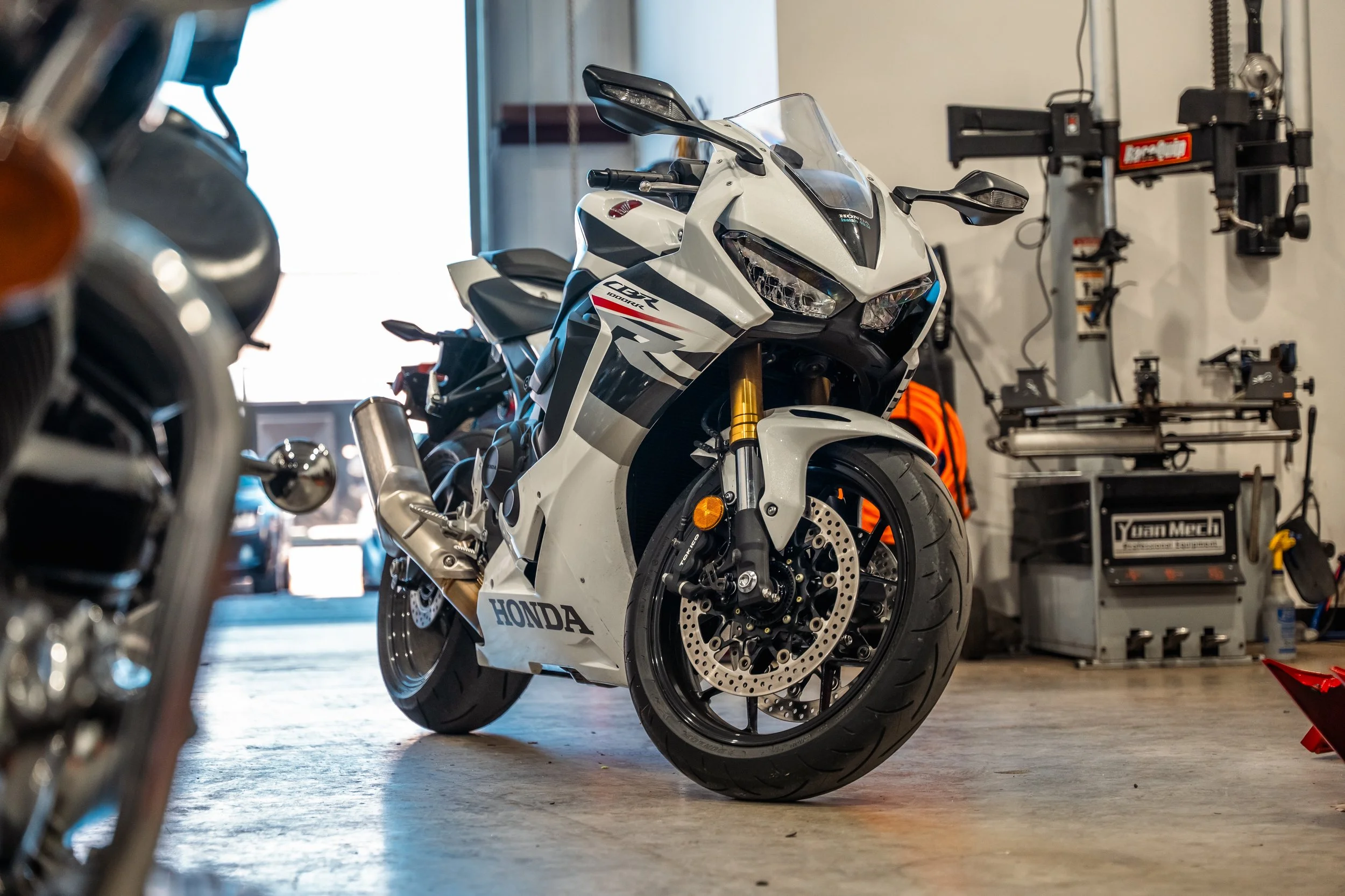 White Honda sport motorcycle in a garage with workshop equipment.