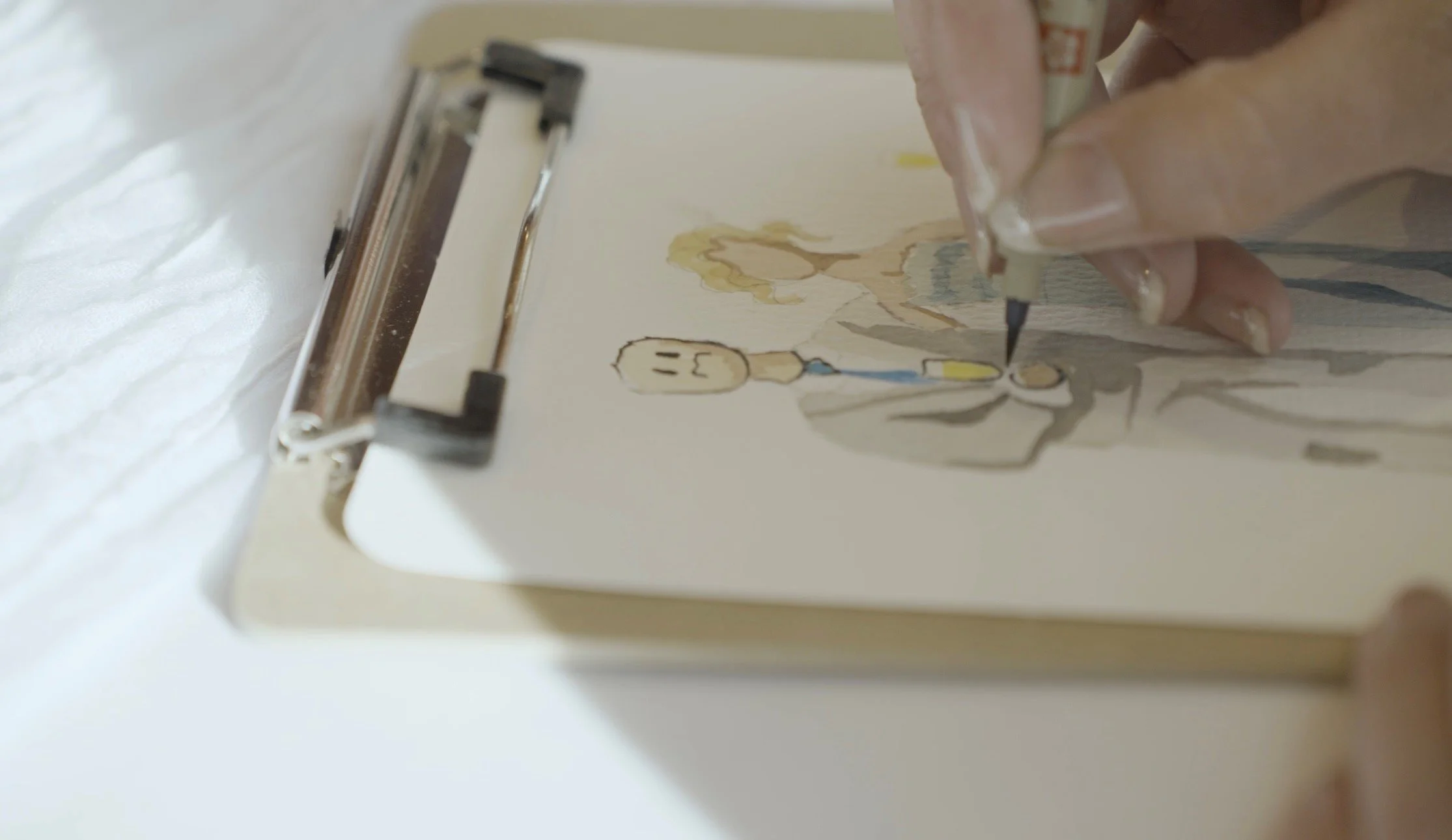 A person colouring a custom character on paper using coloured markers, with a clipboard underneath.
