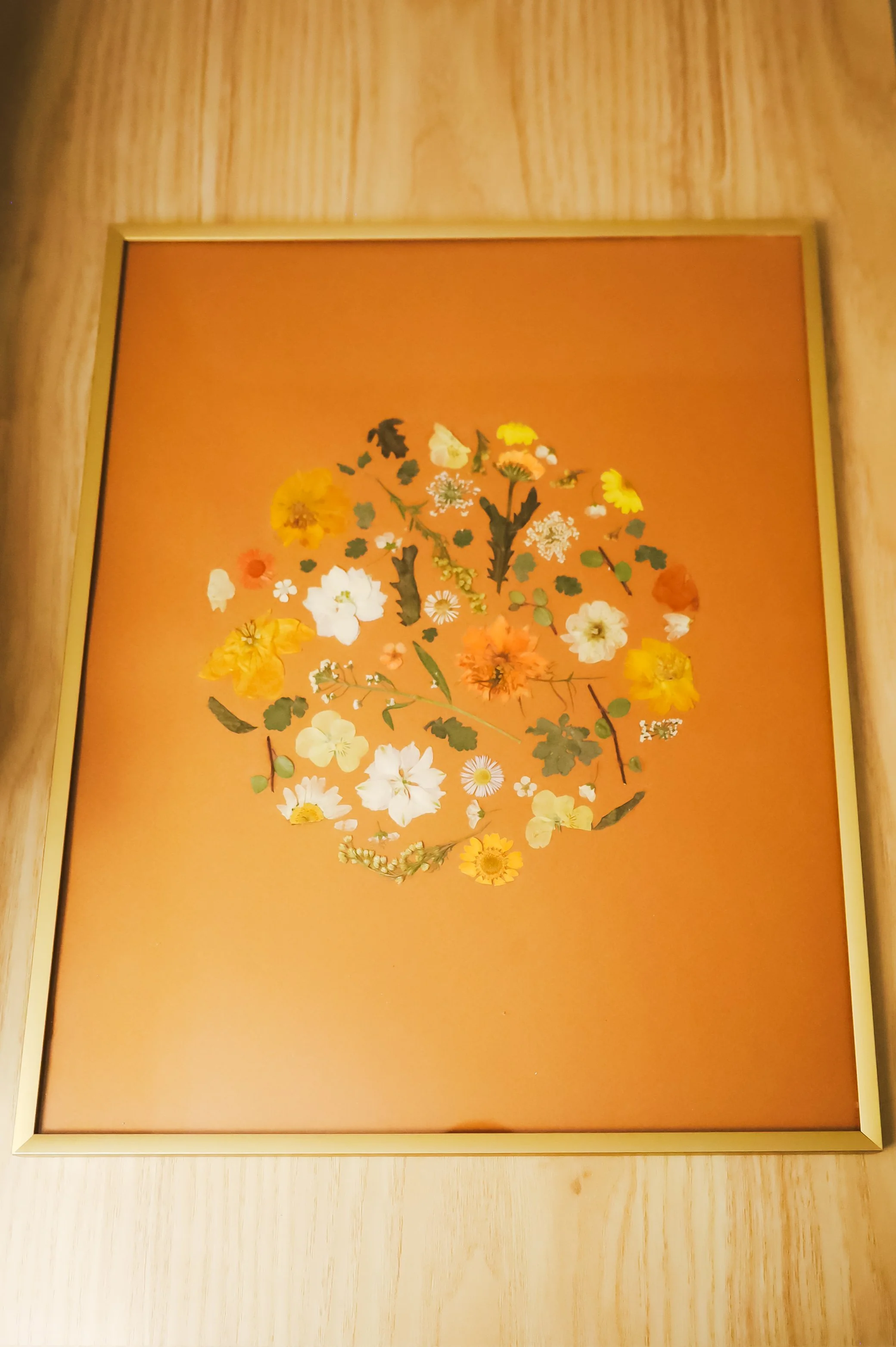 Framed artwork of a floral arrangement on a brown background.