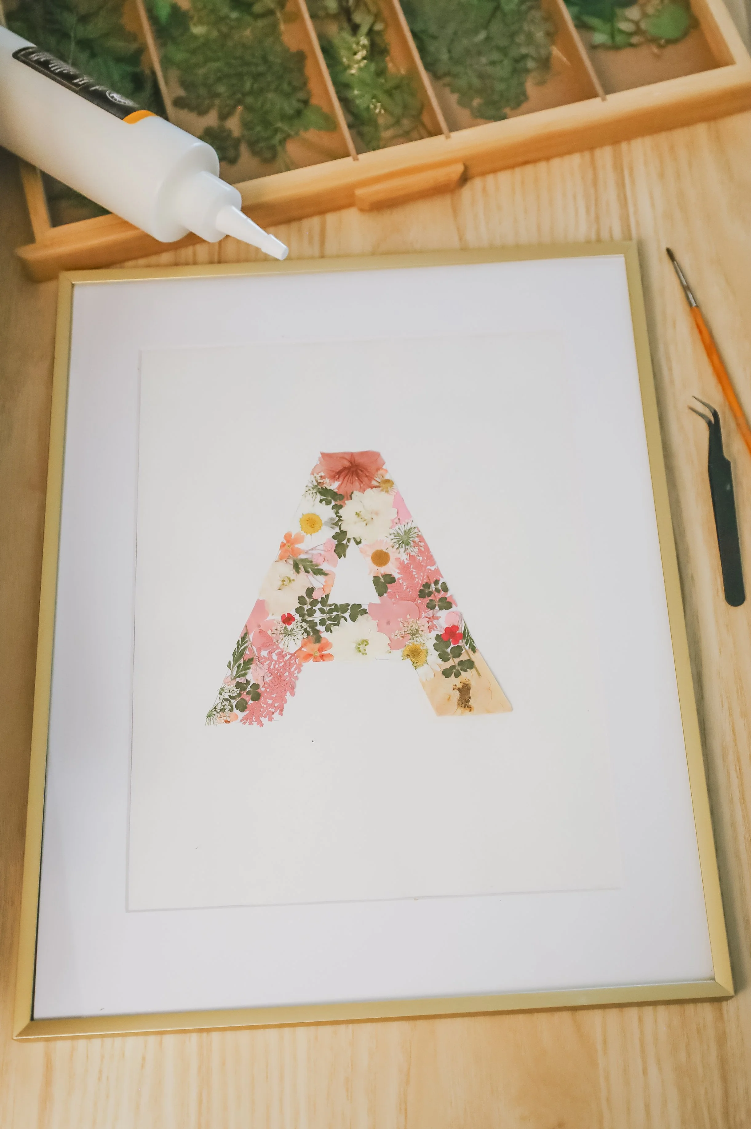 The letter A decorated with various flowers arranged in a floral pattern on a white background.