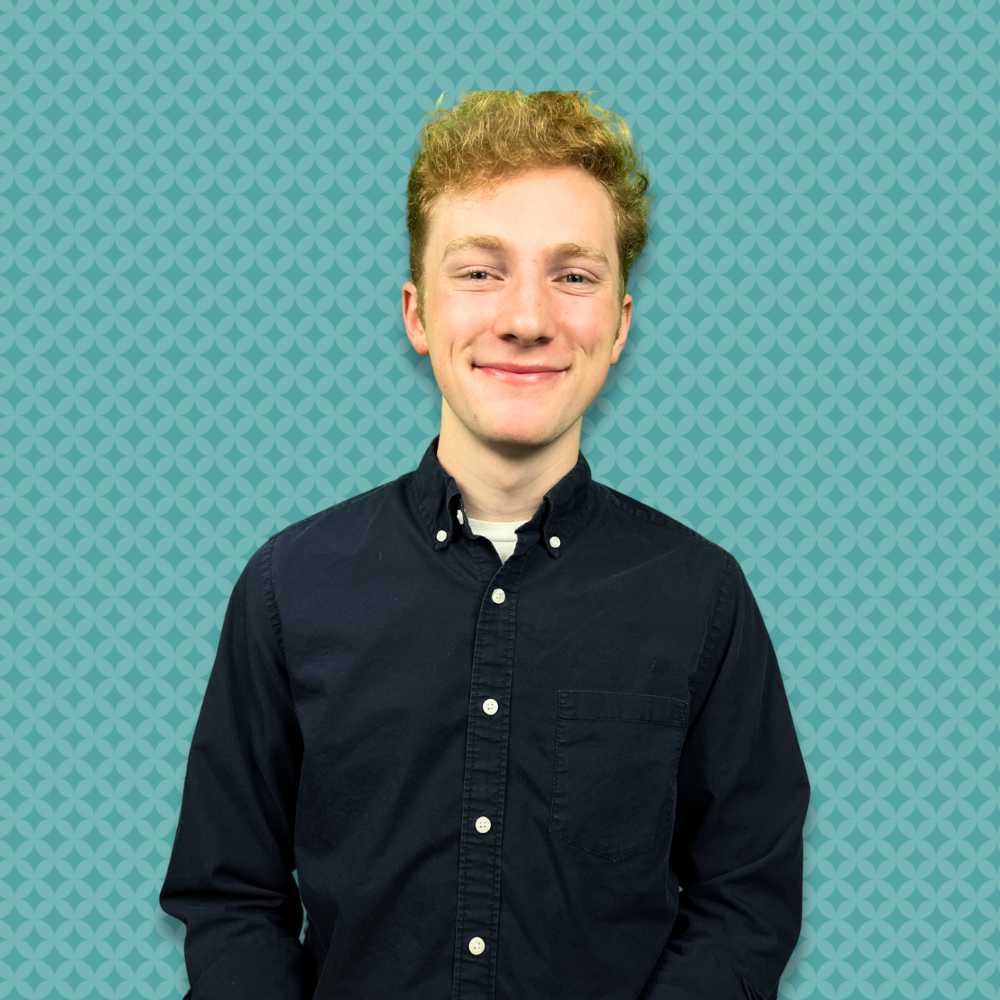 A young man with curly blond hair smiling, wearing a black button-up shirt, standing against a teal background with a repeating geometric pattern.
