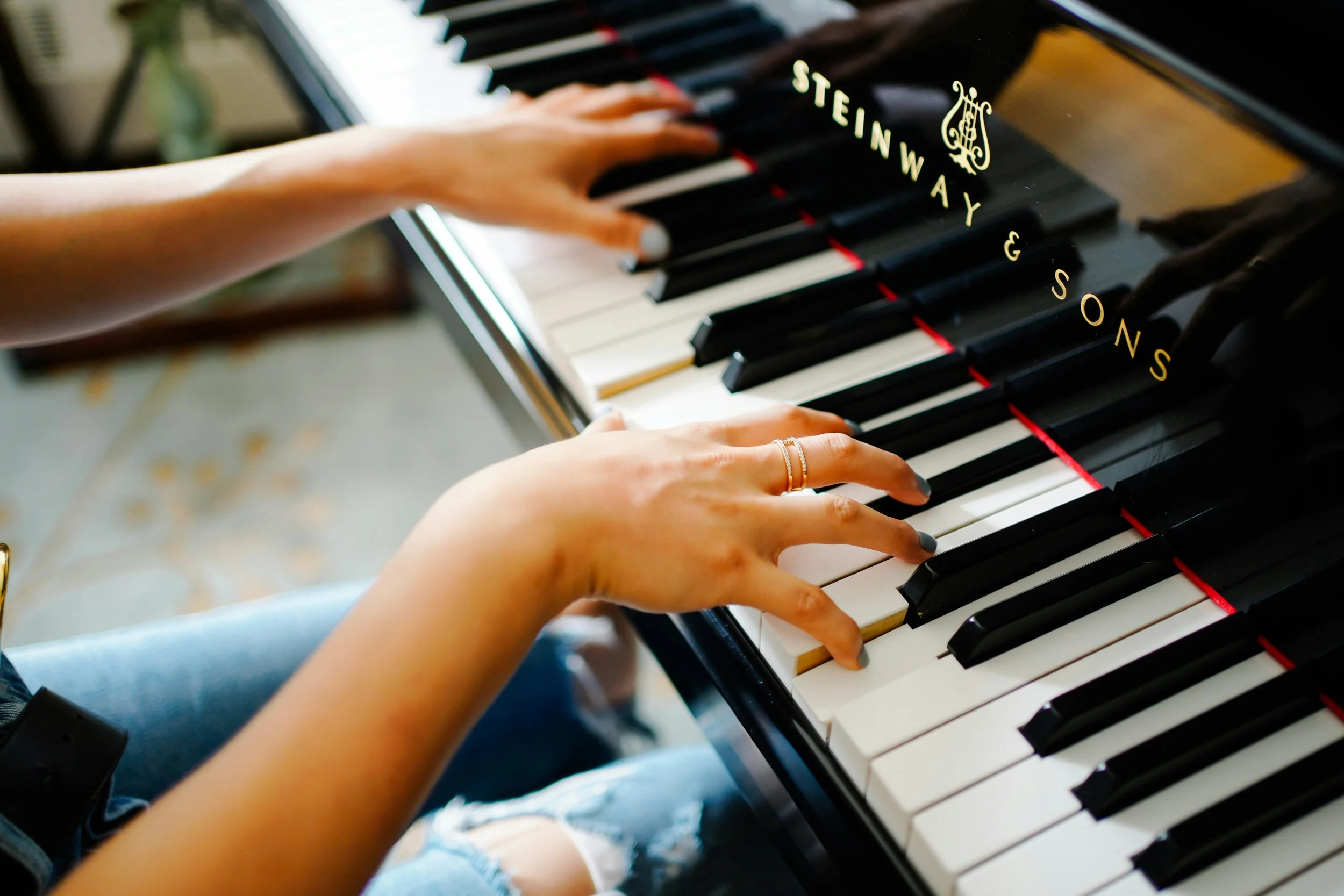 Person playing a Steinway & Sons grand piano, with hands on the keys, seen from above.