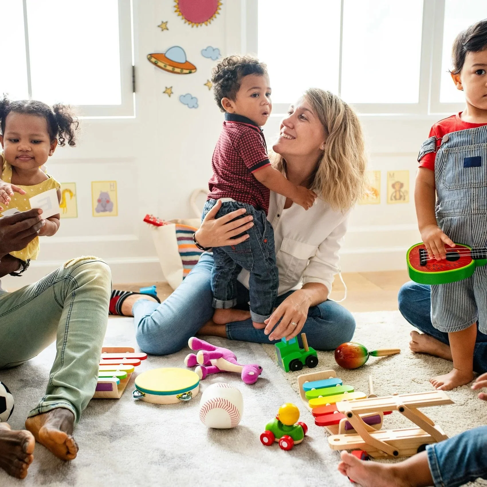 A young girl with long hair, wearing a yellow sweater and a paper crown, playing the piano and looking at the camera.