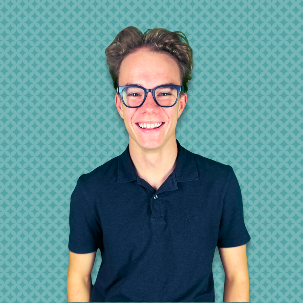 A smiling person with short, wavy hair, wearing dark glasses and a dark polo shirt, standing in front of a teal background with a geometric pattern.