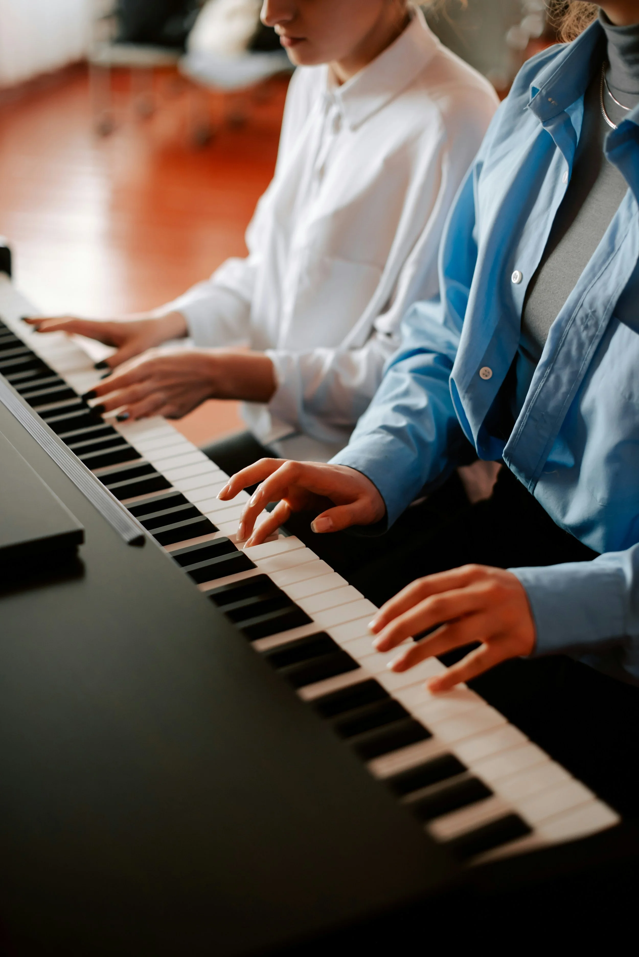 A woman sitting indoors playing an acoustic guitar, wrapped in a chunky knit blanket