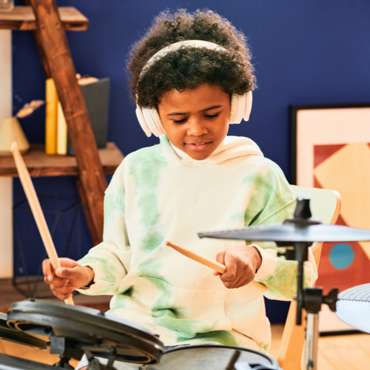 Child wearing headphones playing electronic drum set in a room.