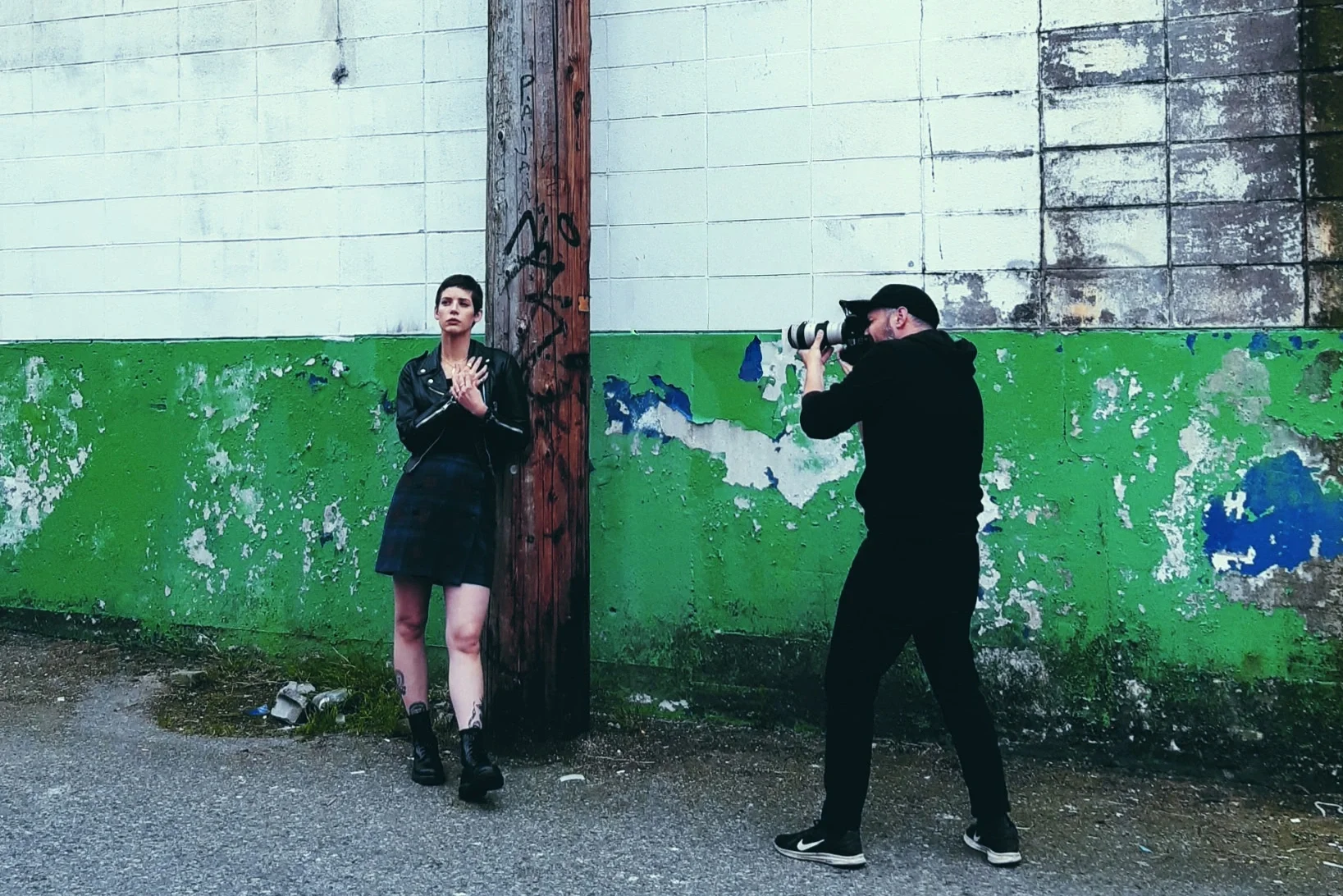 A model posing against a weathered wall with a green lower half, photographed by Ryan Water Wagner.