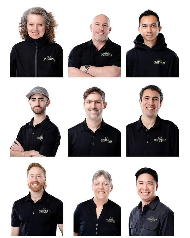 Group portrait of nine people wearing black shirts or hoodies with a company logo, smiling against a white background.