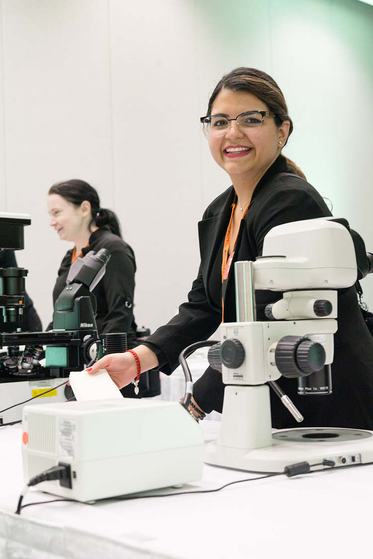 Two women in lab coats working with microscopes in a laboratory.