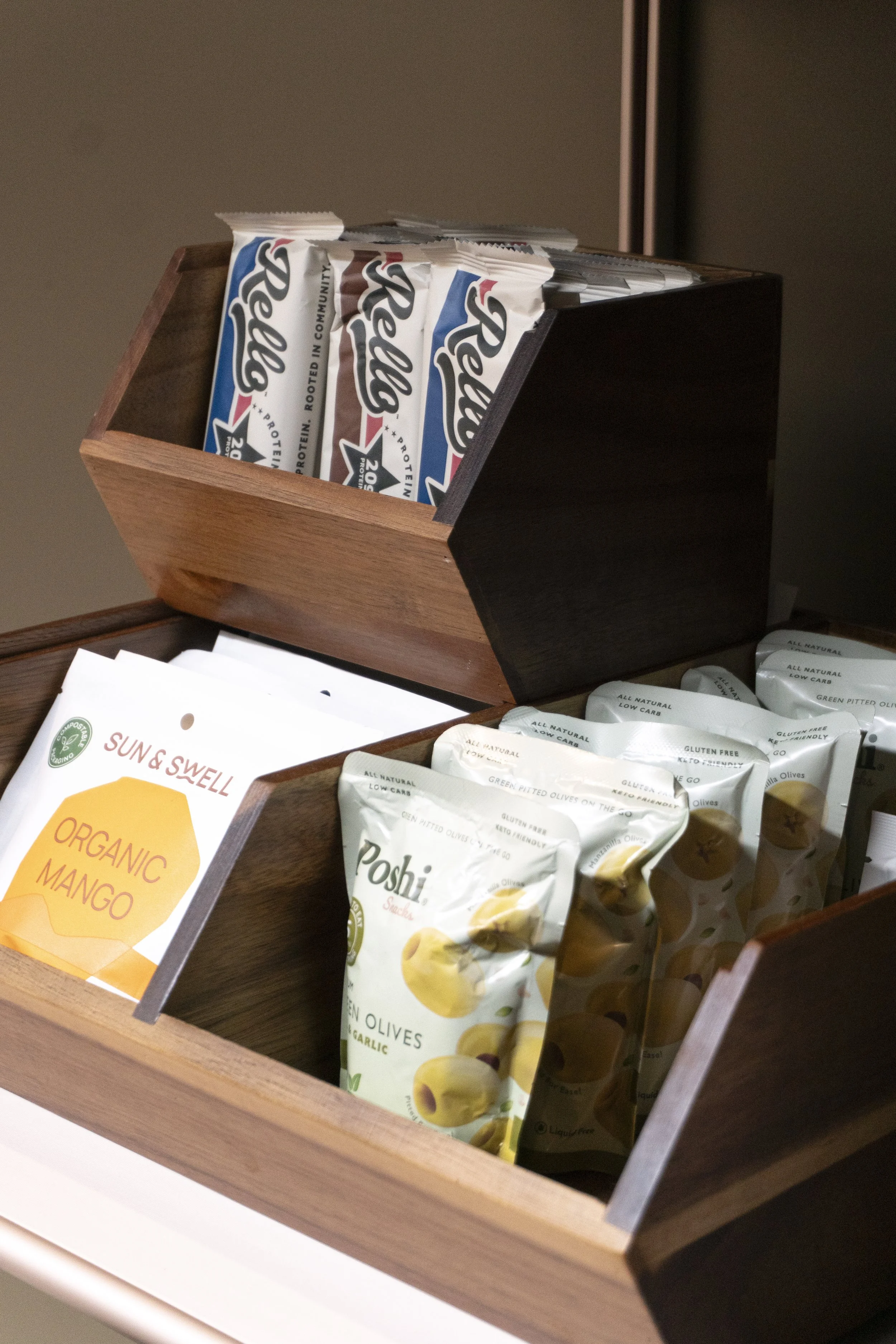 Wooden box with protein bars on top and snack packets inside.