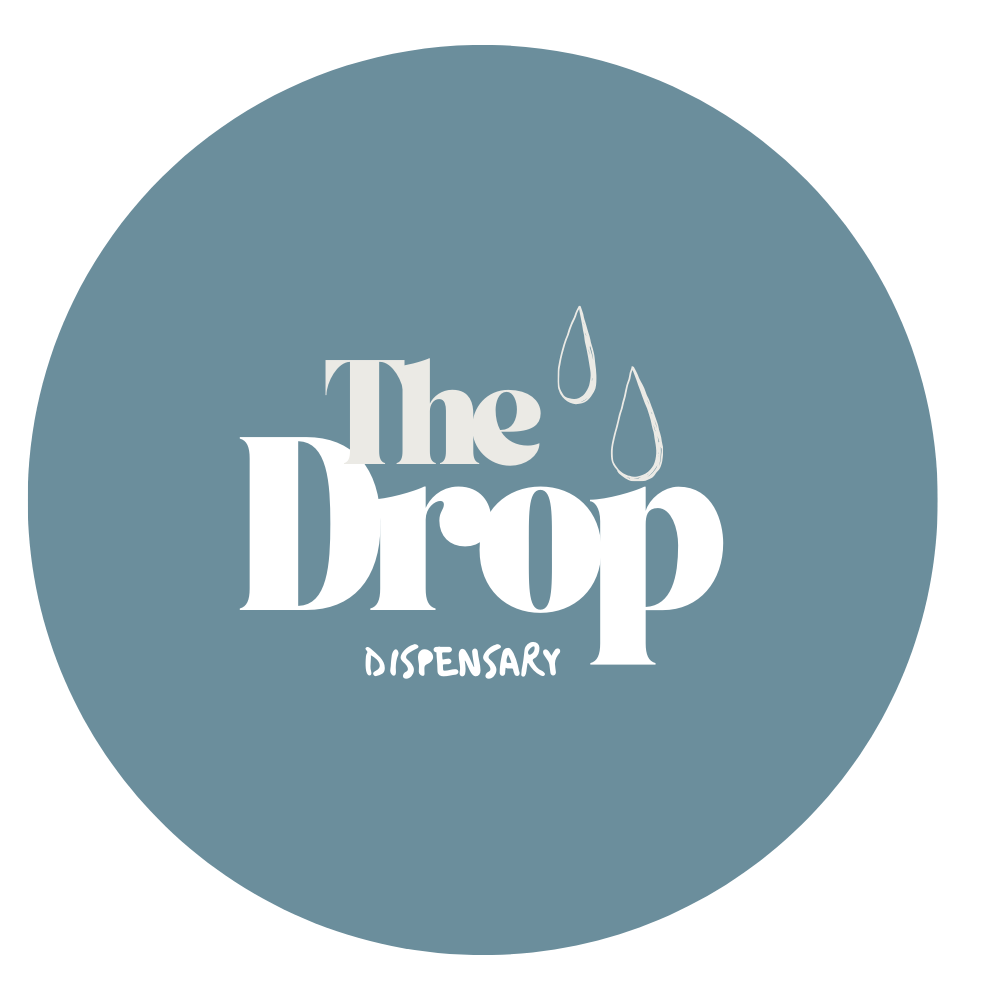 Logo for The Drop Dispensary with a dark teal circular background, featuring the text 'The Drop' in large white font, smaller handwritten 'Dispensary' beneath, and two droplet icons above the text.
