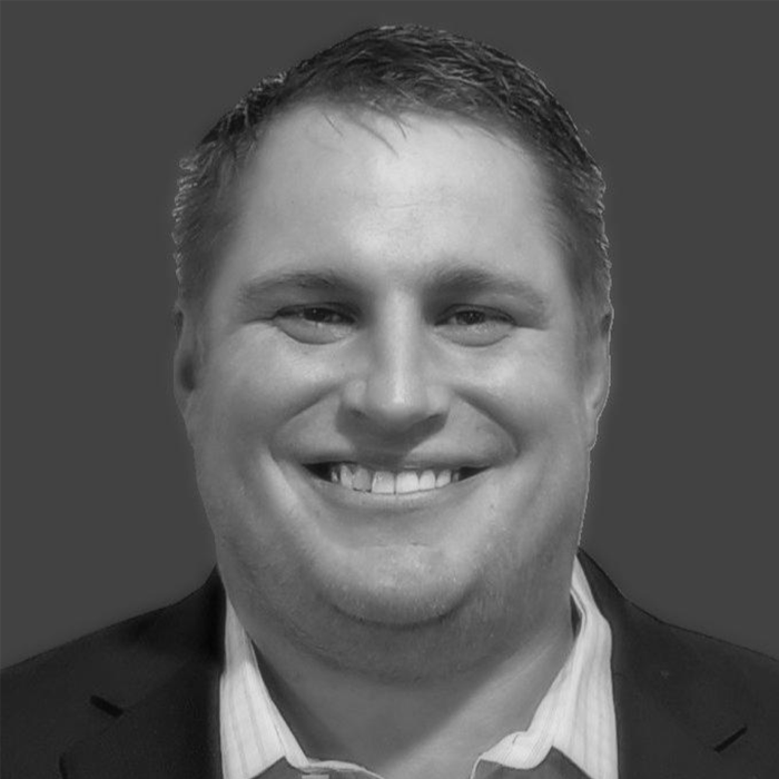 Black and white portrait of a smiling man wearing a suit and collared shirt.