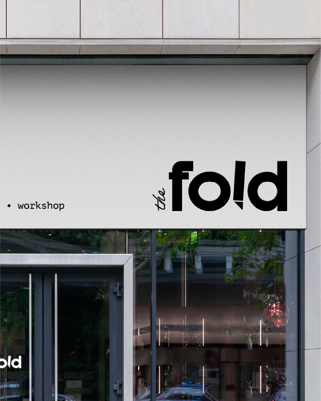 Sign for the fold workshop on a modern building exterior with large glass windows.