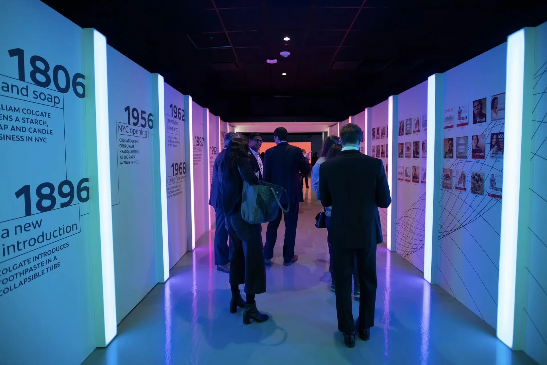 People walking through a colorful exhibition hallway with historical timeline panels on the walls.