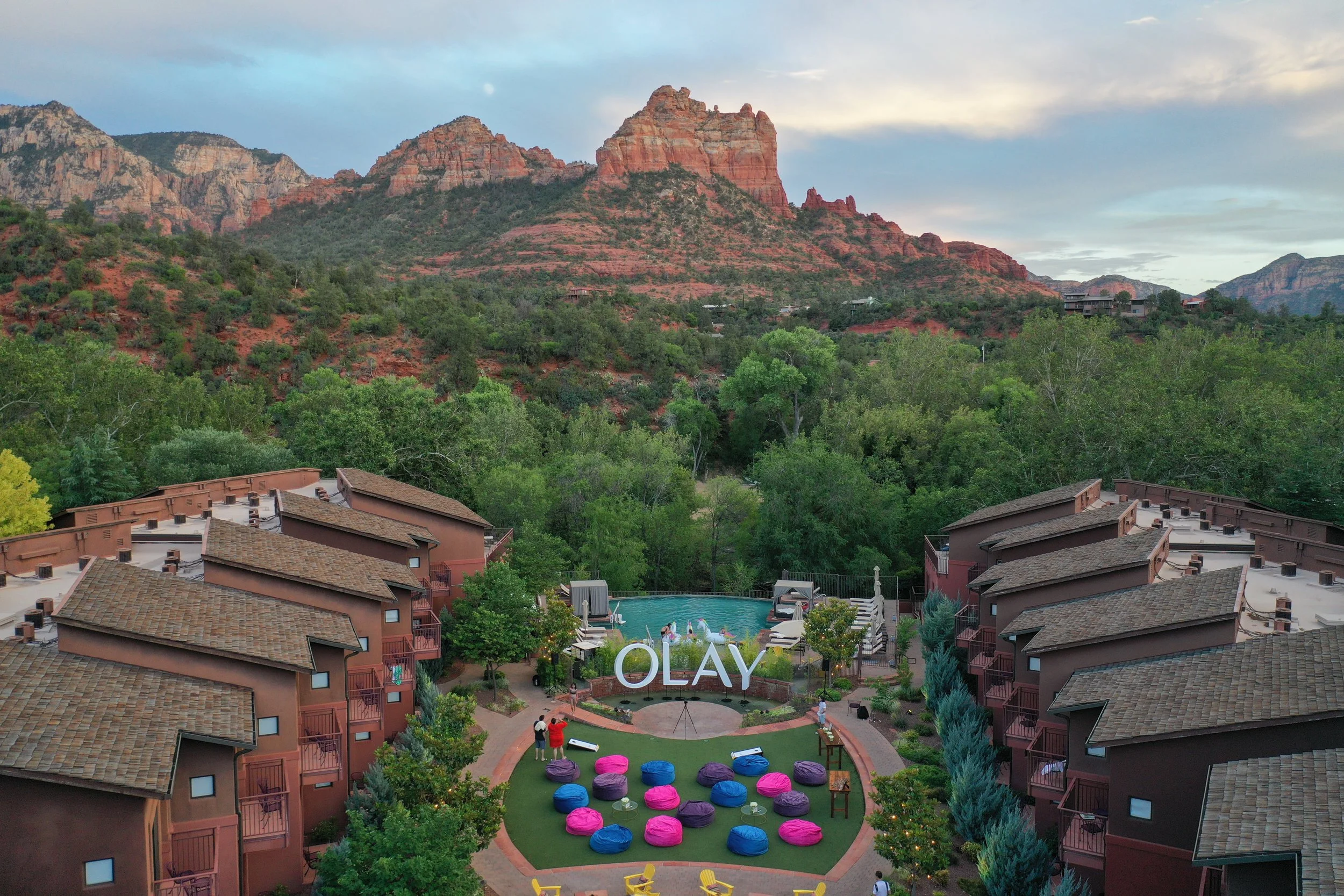 Resort with Adobe-style buildings surrounded by greenery, a pool, and colorful bean bags in a circular arrangement with a mountainous desert landscape in the background.