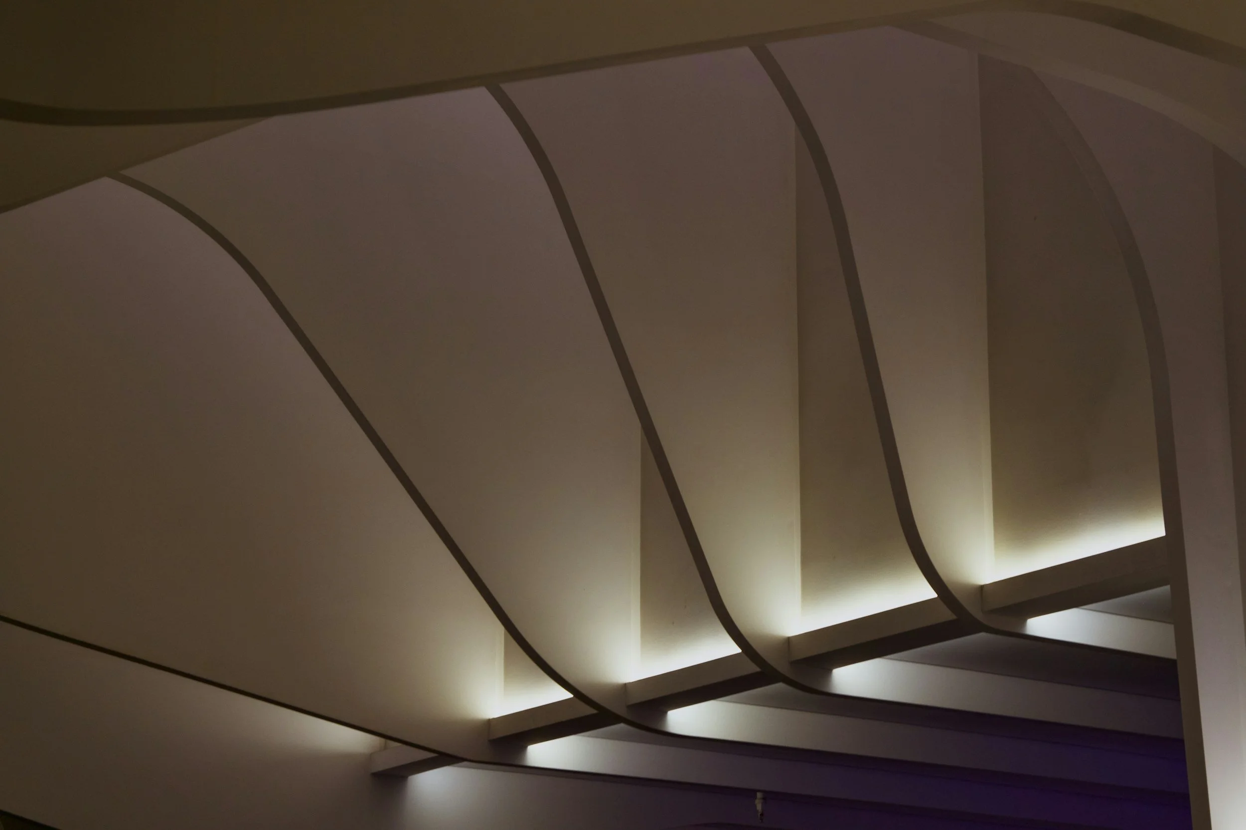 Close-up of a modern ceiling design with curved panels and indirect lighting.