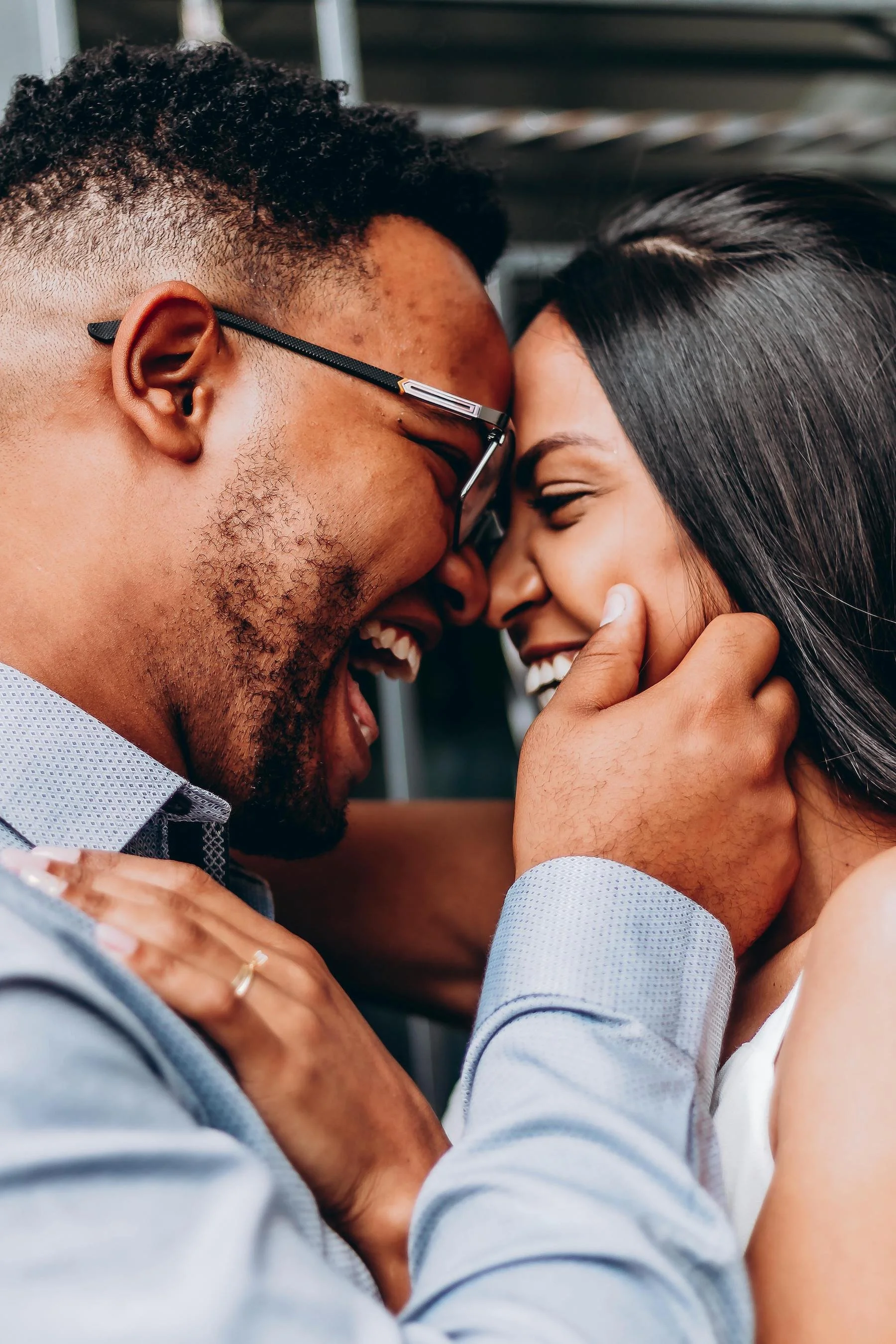 A couple sharing a joyful embrace with their foreheads touching and smiling at each other.