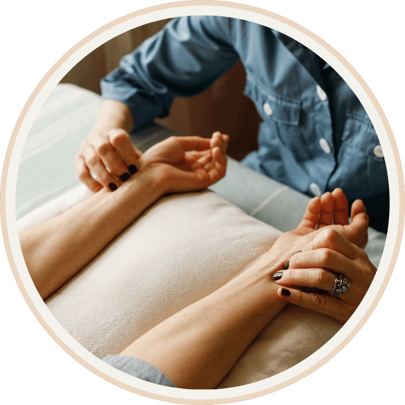 A person lying on a bed holding hands with another individual who is providing comfort or support.
