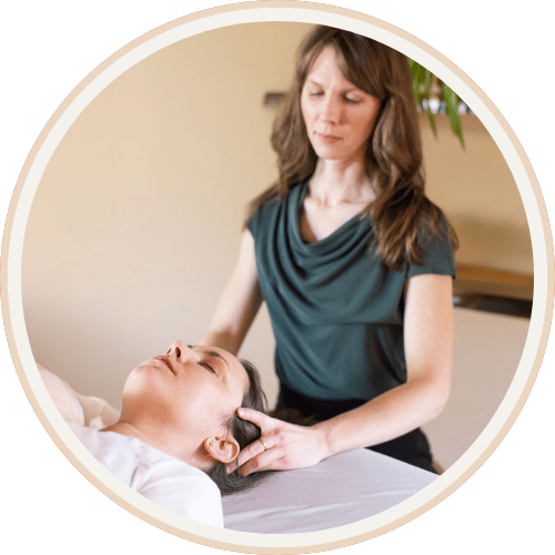 Acupuncturist Jennifer Peterson performing cranial or manual therapy on a patient lying on a treatment table at Current Wellness in Portland, OR