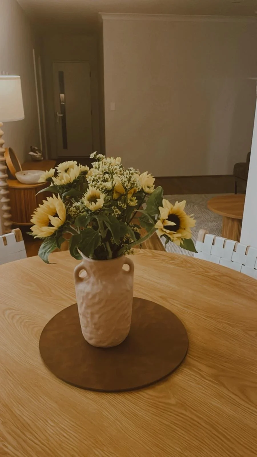 A vase with white flowers on a wooden table in a living room.