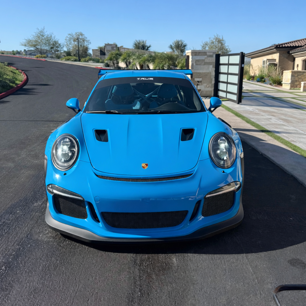 Mexico blue Porsche GT3 RS car parked on a paved driveway in front of a modern house with stone accents and a landscaped yard.