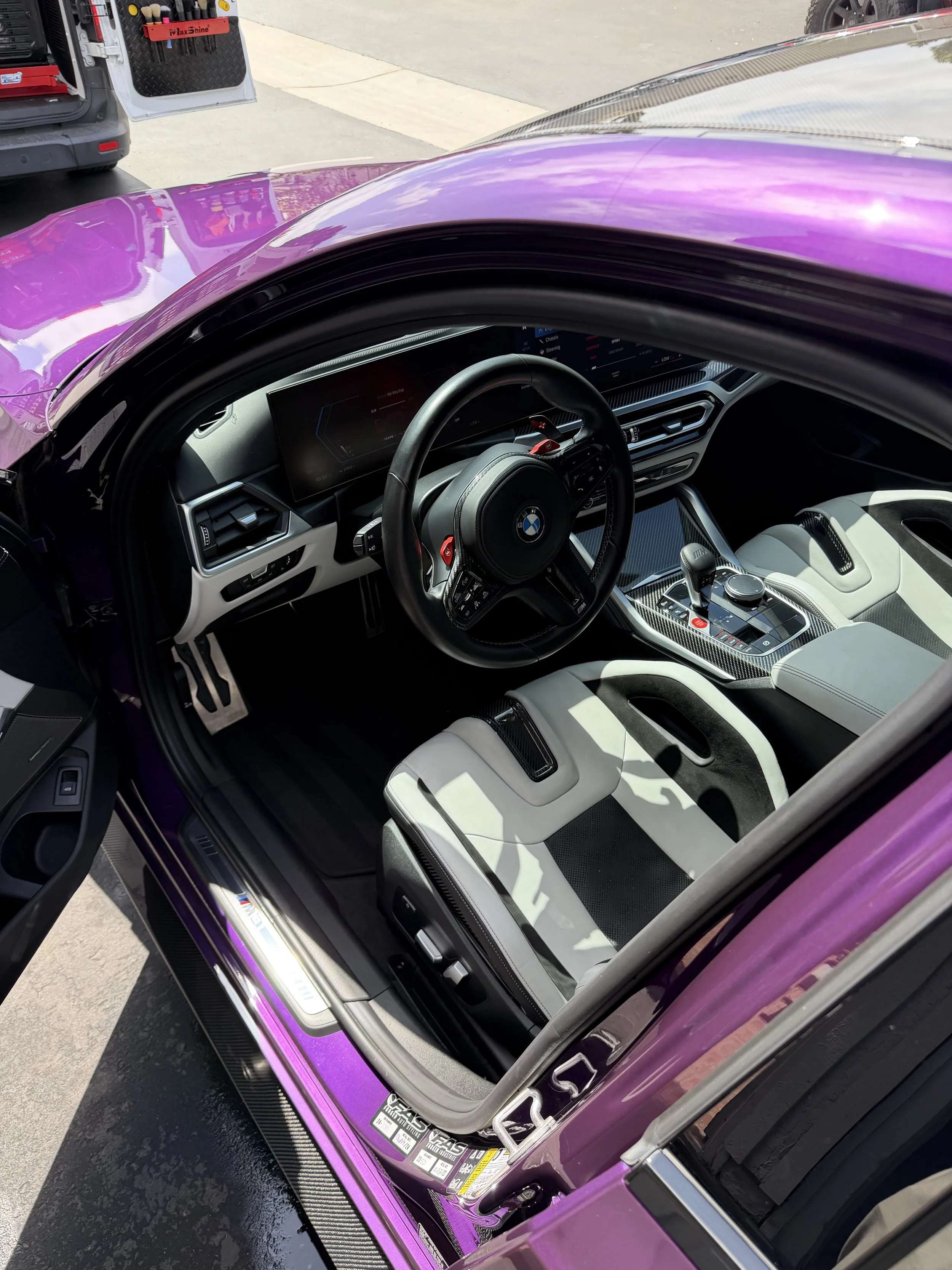 Interior view of a luxury car with a purple exterior, racing-style steering wheel, digital dashboard, and white leather seats.
