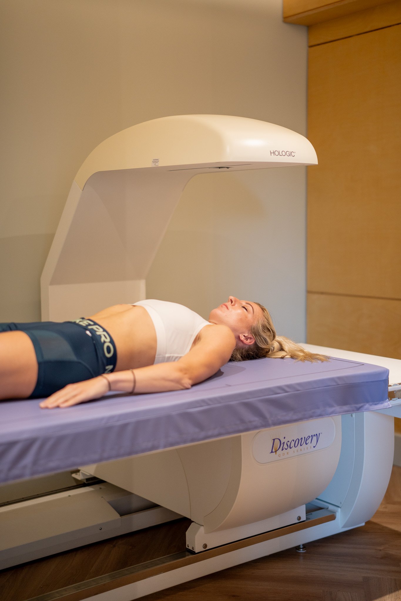 A woman lying on a medical imaging machine called a DEXA scanner for a full body composition scan.