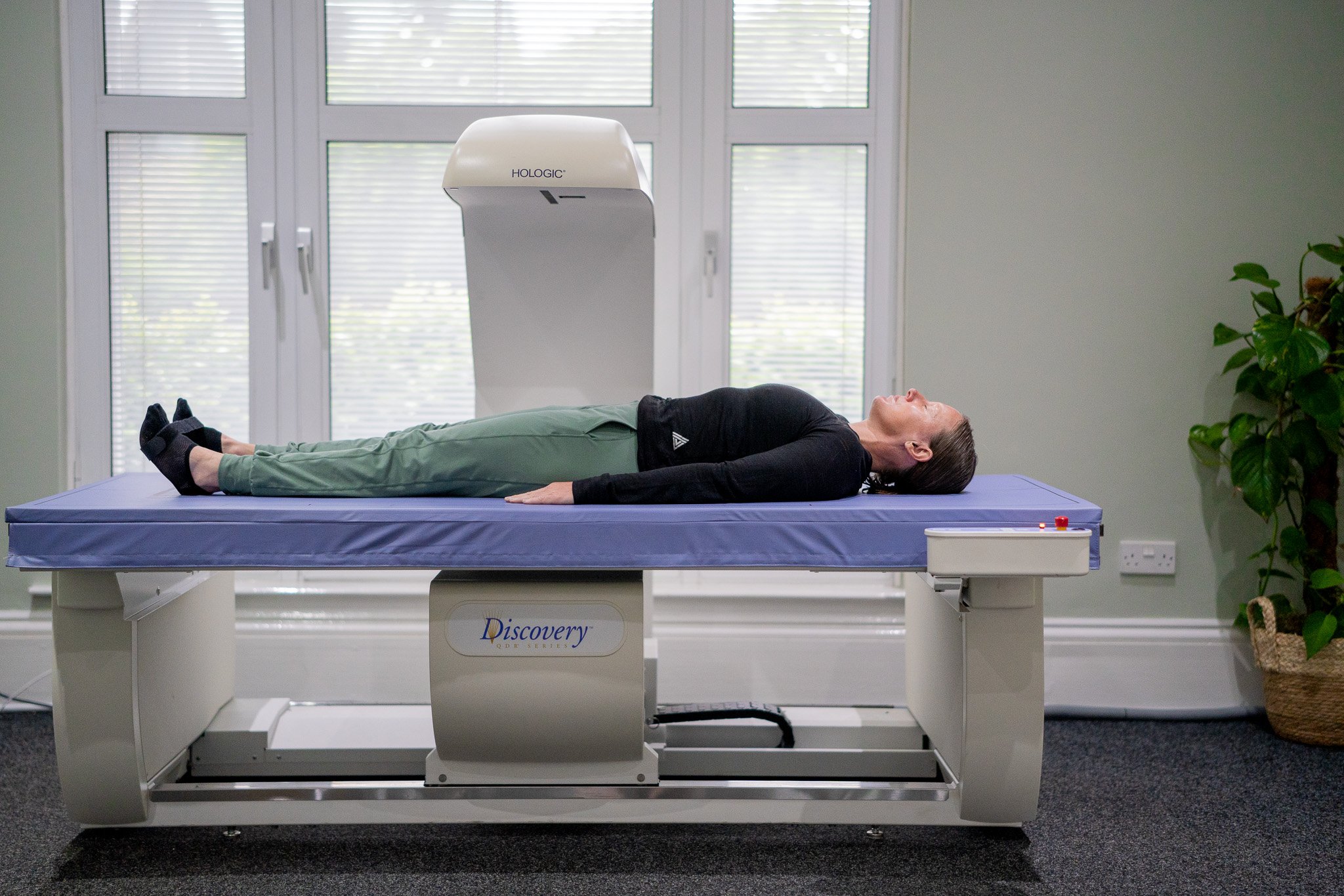 A lady lying on her back on a DEXA scanner, smiling and looking relaxed.