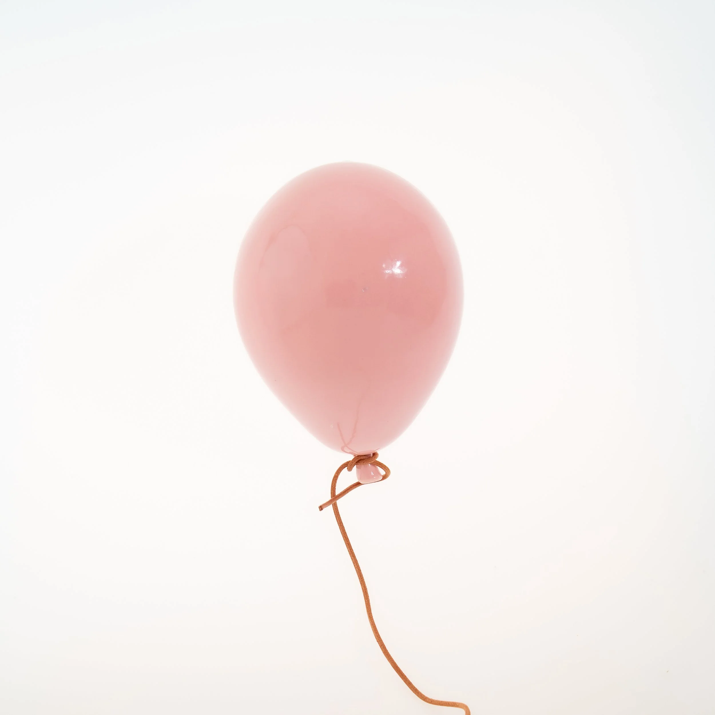 A pink balloon with a brown string tied to its bottom, floating against a plain white background.