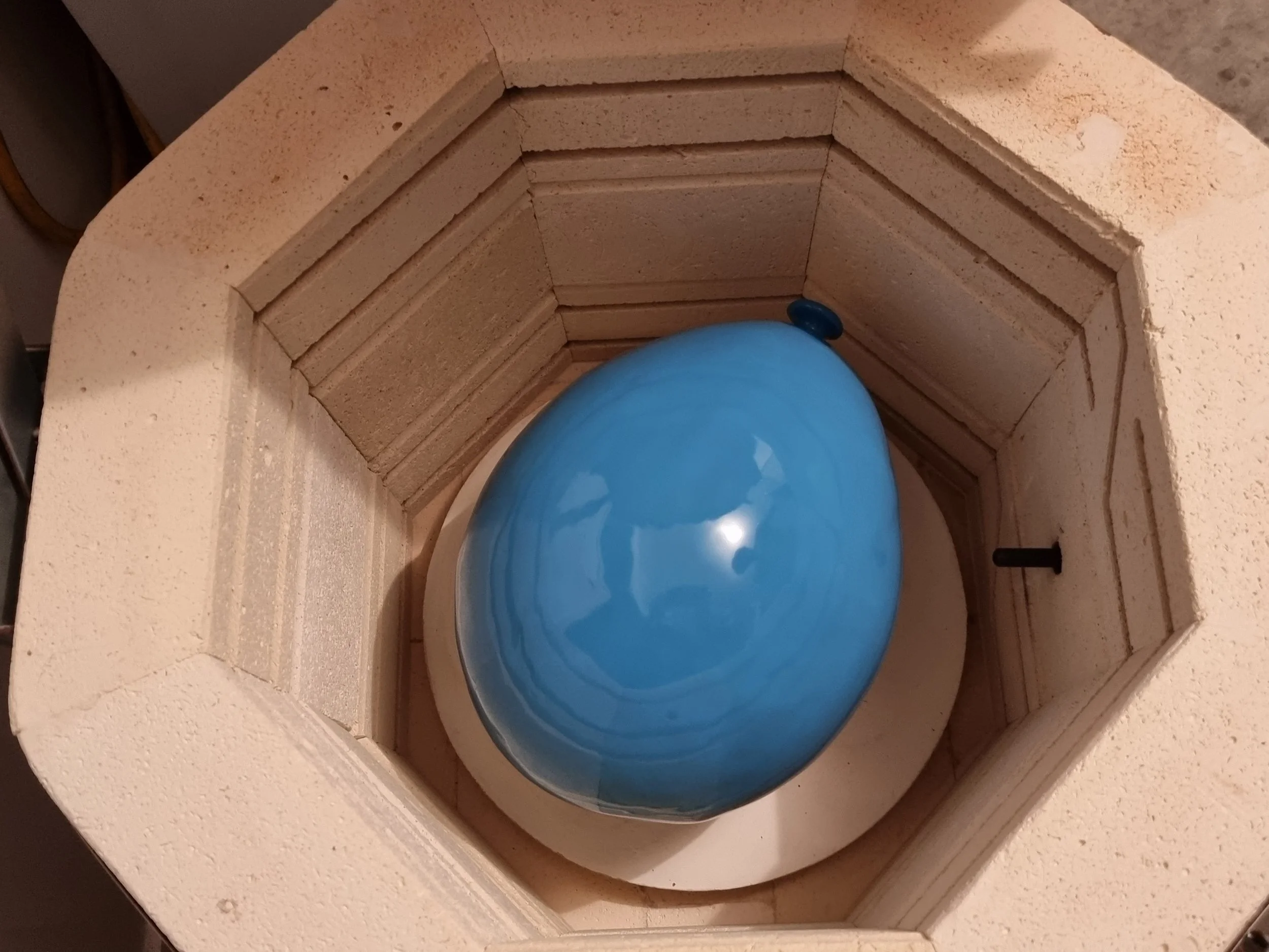 A blue, egg-shaped object inside a white, octagonal brick fireplace.