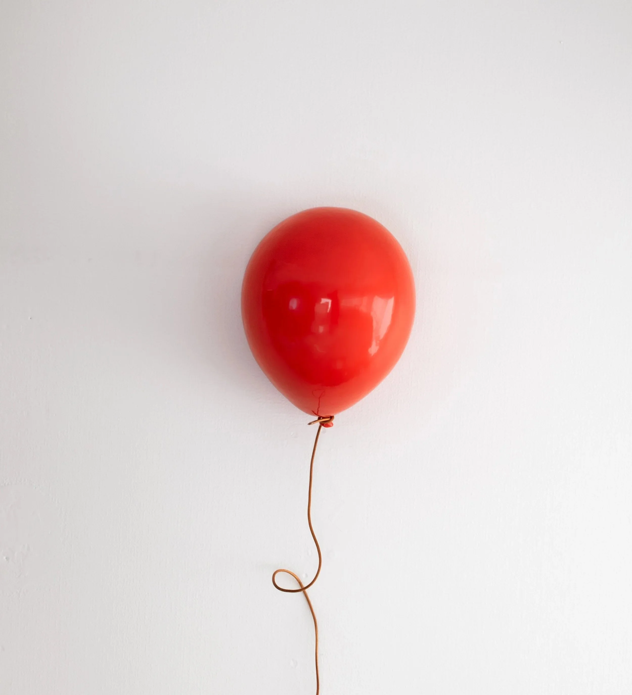 Scenic landscape of mountains, a lake, and rolling grassy hills with sparse trees under a cloudy sky.