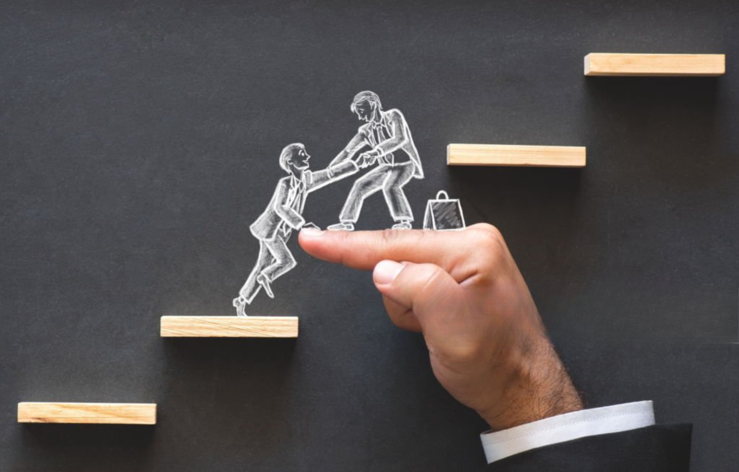 A person's hand points to a chalk drawing on a black background showing an adult helping a child walk across a gap, with small wooden platforms representing the gap.