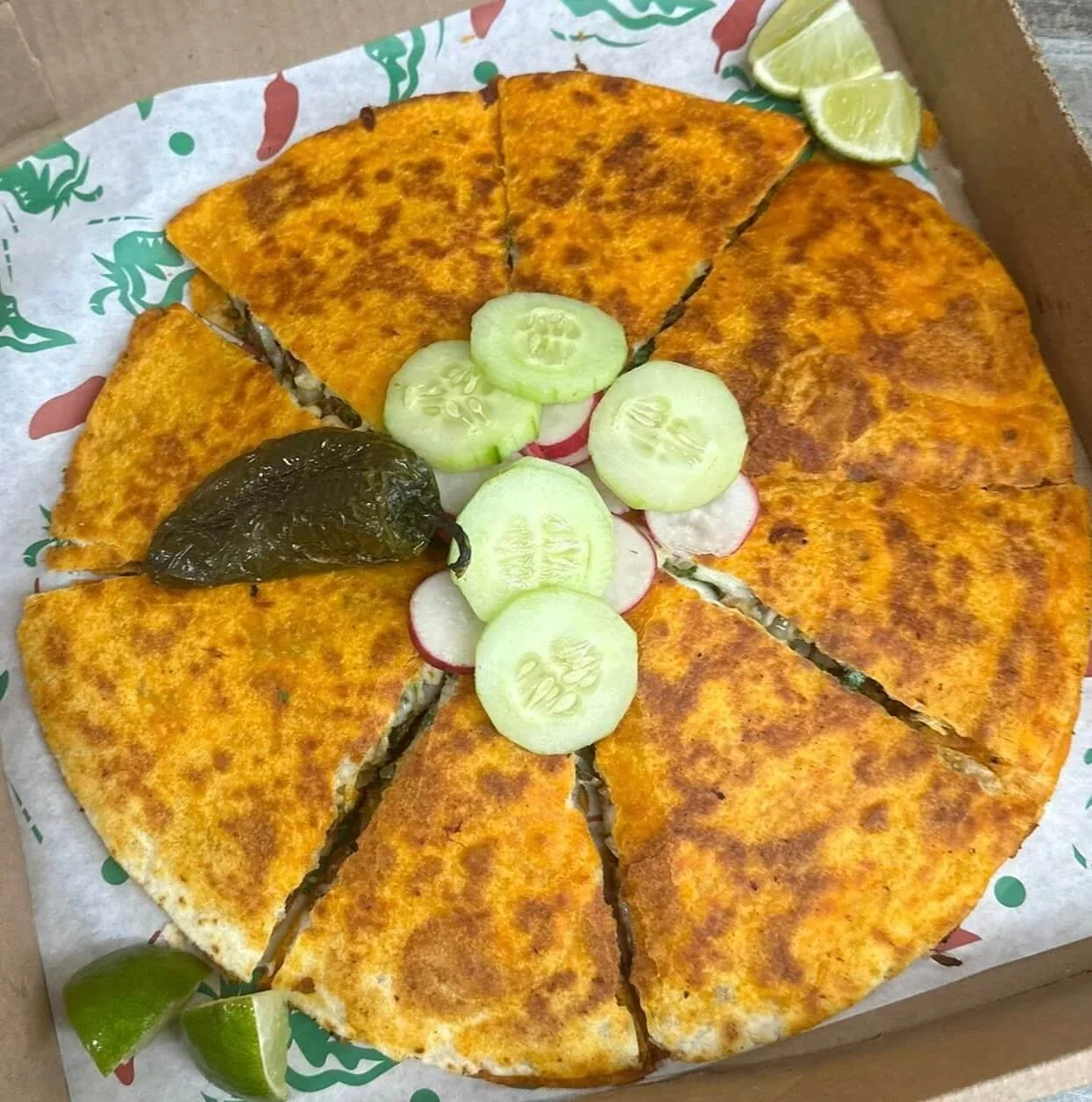 lapaisanita-starkville-birria-pizza.jpg → Birria pizza topped with sliced cucumbers, radishes, a roasted jalapeño, and lime wedges.