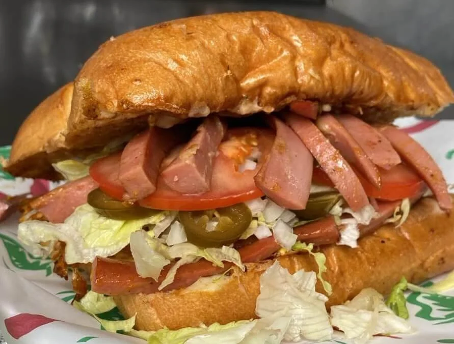 lapaisanita-starkville-sub-sandwich.jpg → Croissant-style sub sandwich filled with ham, lettuce, tomato, and jalapeños.