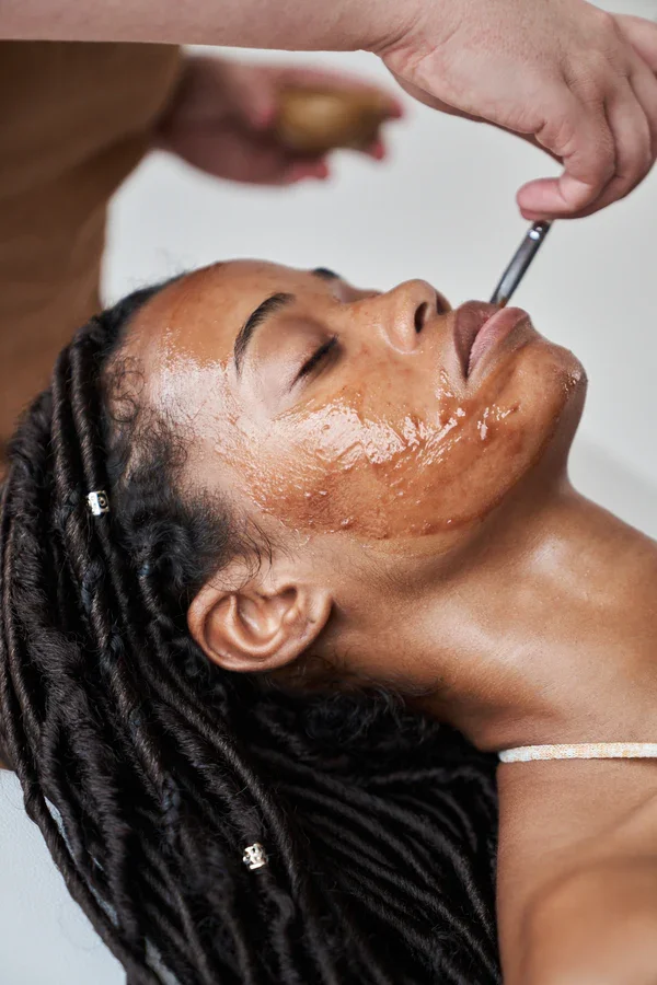 Woman receiving a facial treatment with a skincare product applied to her face in a spa or skincare clinic.