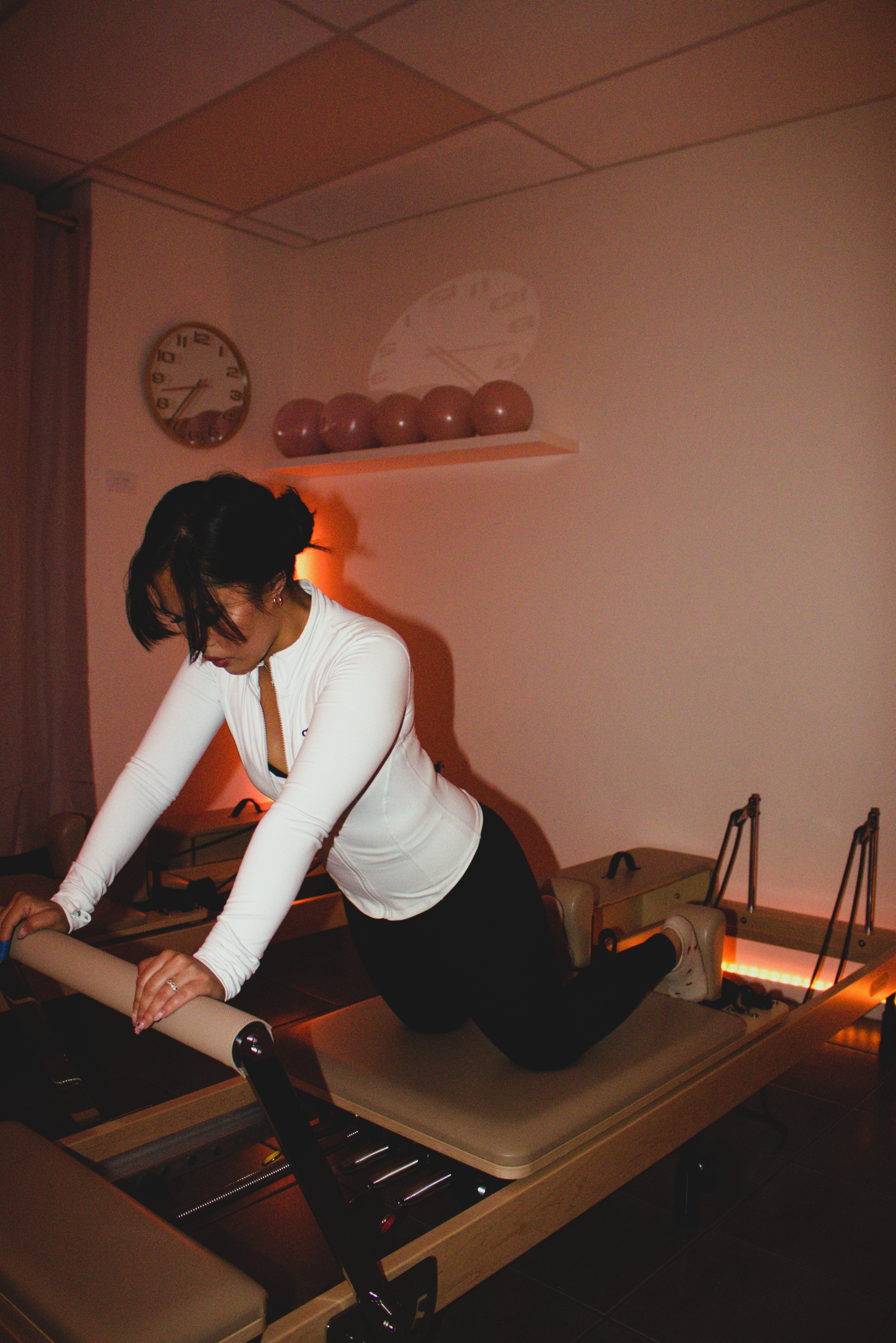A woman performing Pilates on a reformer machine in a fitness studio.