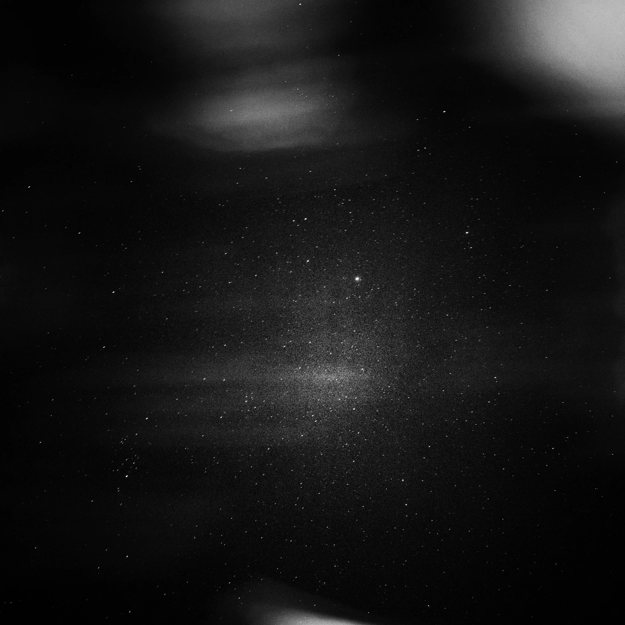 Black and white photograph of a star-filled night sky with clouds.