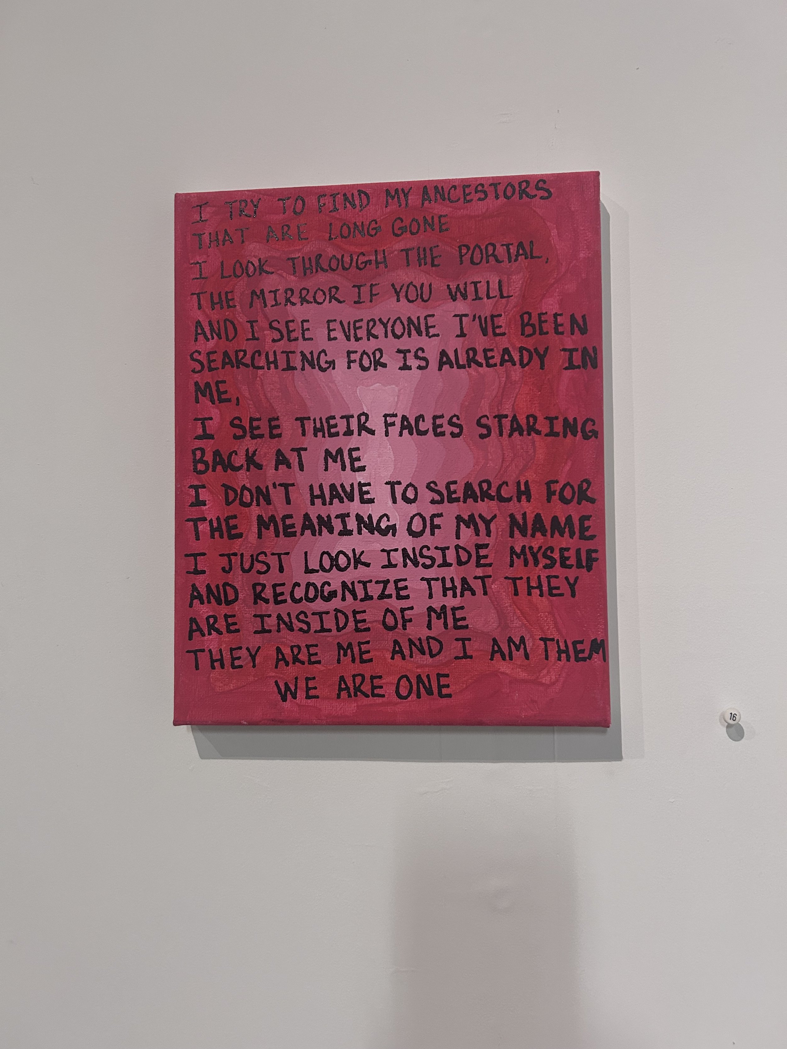 A pink canvas with handwritten black text of a poetic quote, hung on a white wall.