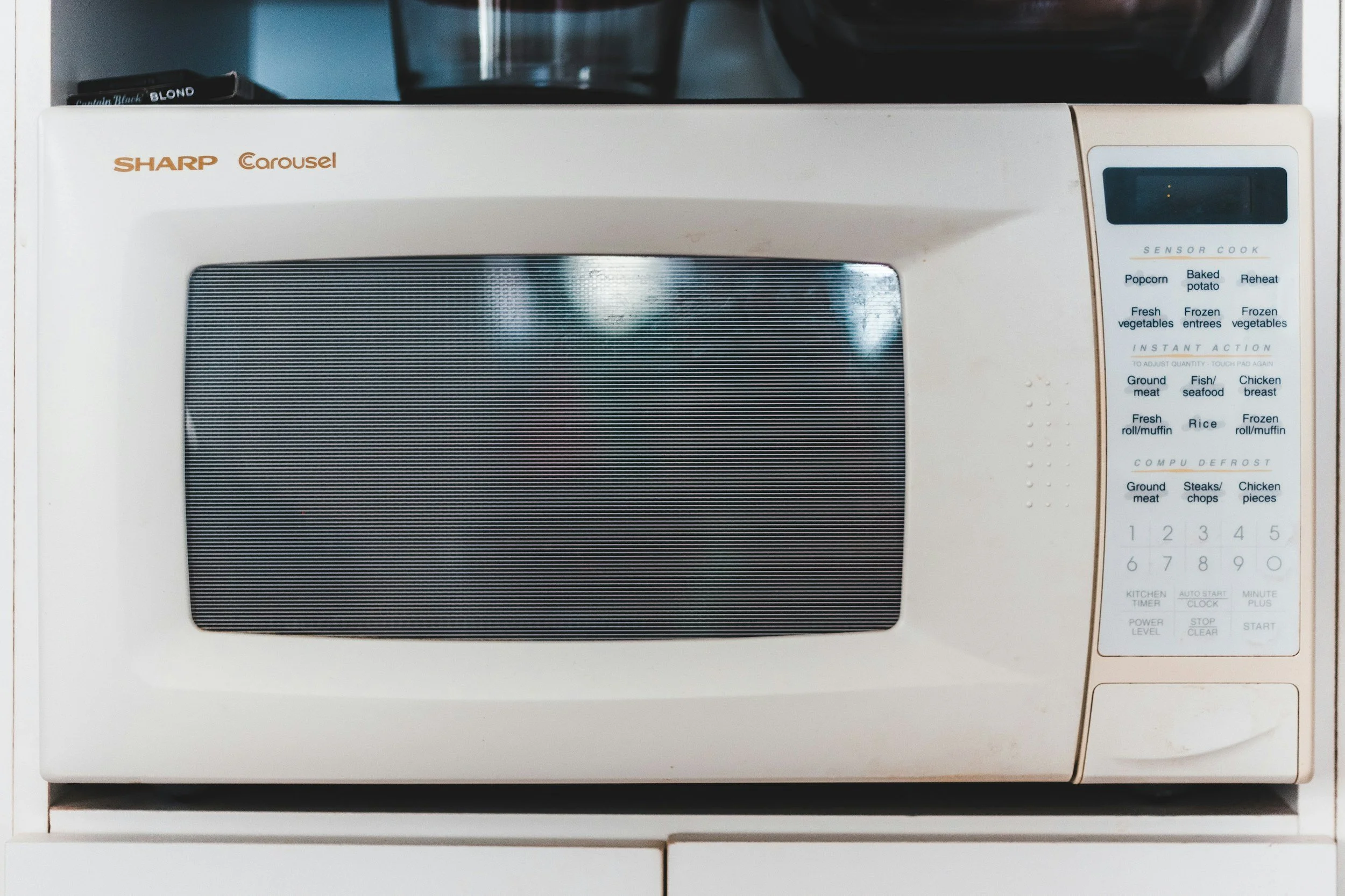 A white Sharp Carousel microwave oven with a digital control panel on the right side on a kitchen countertop.