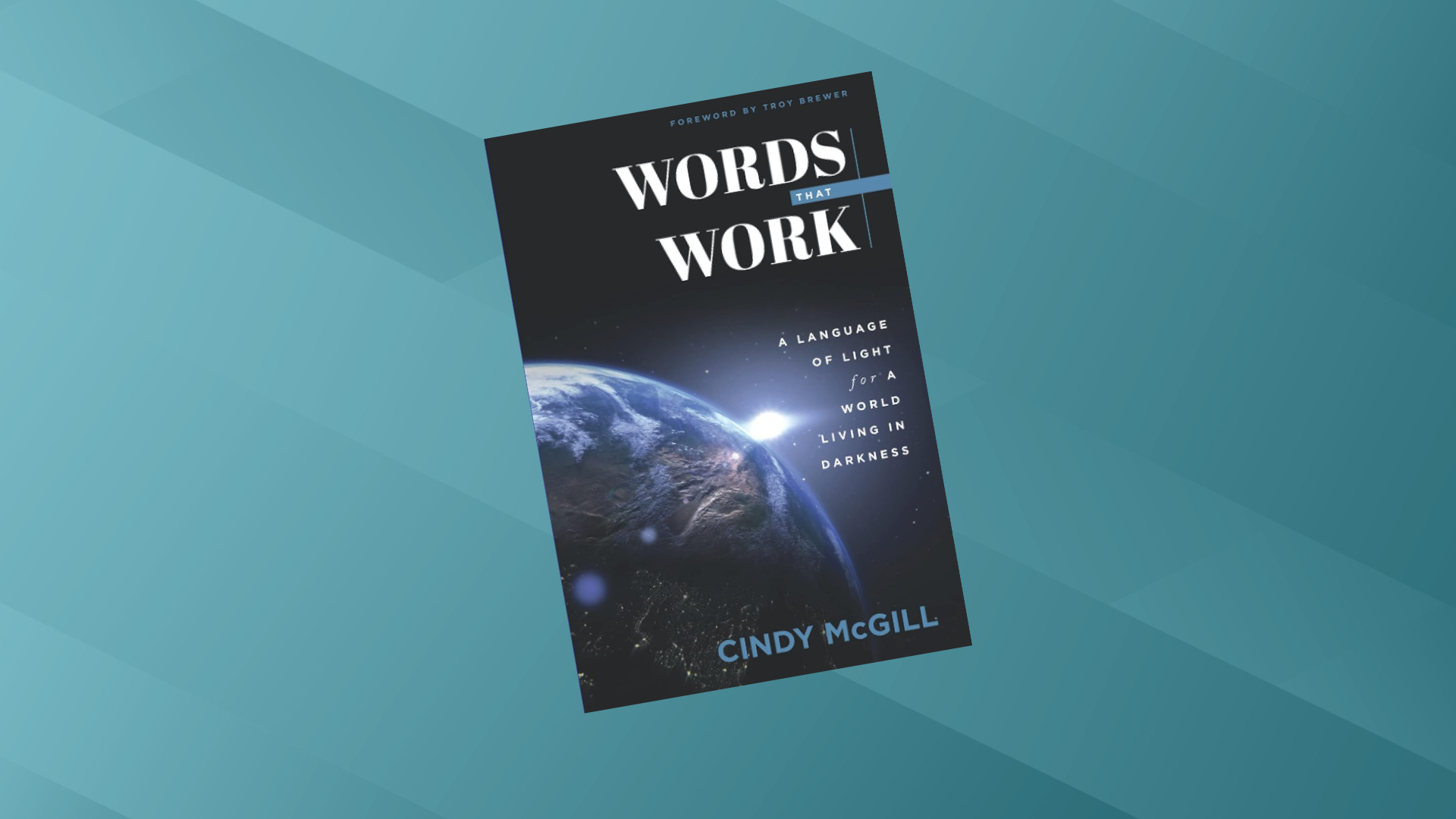 The book titled 'Words That Work' by Cindy McGill, with a subtitle indicating it is about language and living in darkness, features a cover image of Earth from space with a bright light illuminating it against a dark background.