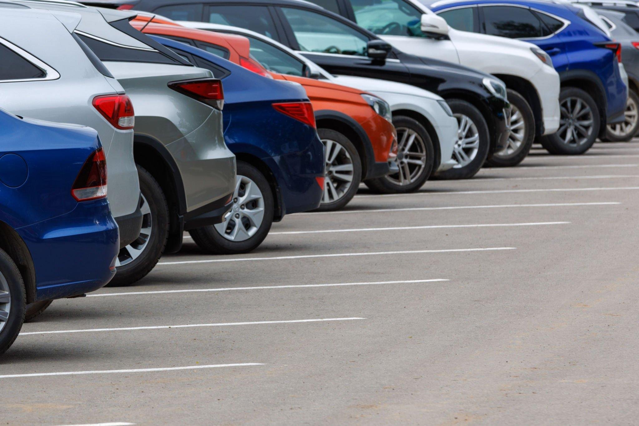 Multiple parked cars in a parking lot, lined up in designated parking spaces.