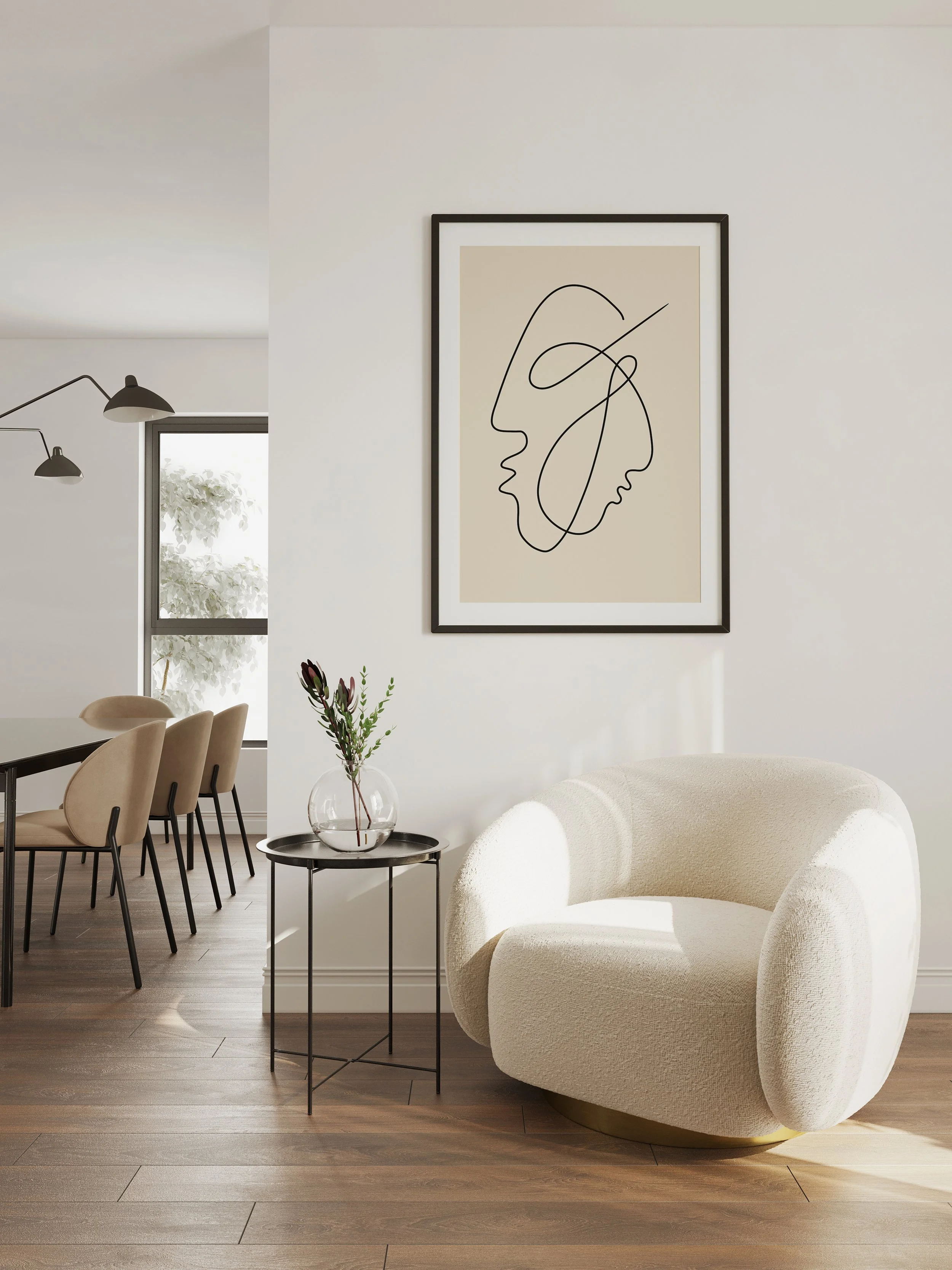 Modern living room with a cream curved armchair, black side table with a glass vase and green plant, framed abstract line art on the wall, and dining area with beige chairs and black table in background.