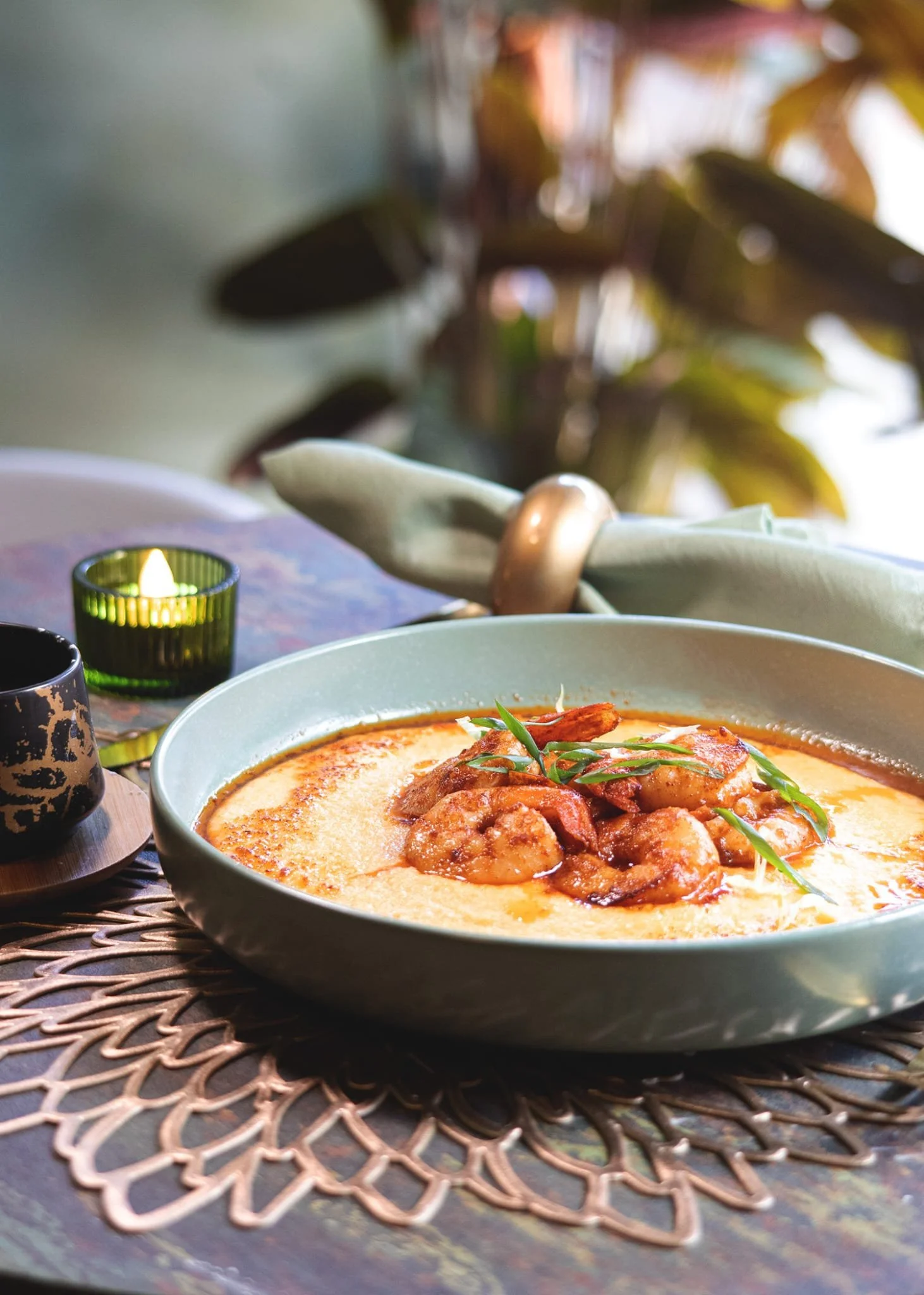 A bowl of cheddar grits topped with succulent seasoned shrimp.