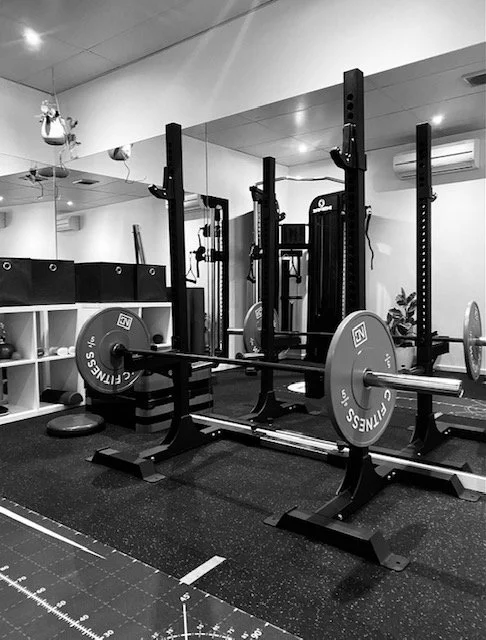 Power rack with barbells and weight plates in gym.