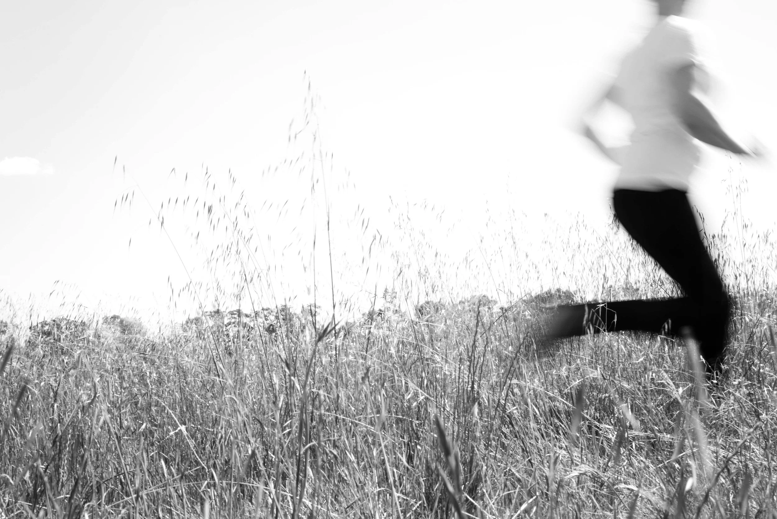 Person running through a grassy field on a sunny day.