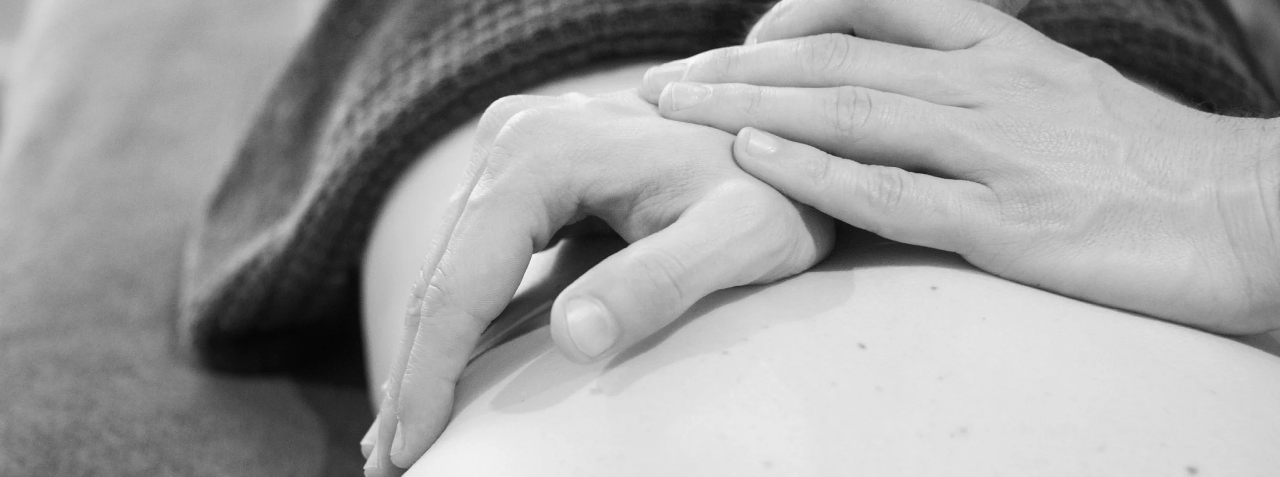 Close-up of a person's hand gently holding another person's hand.
